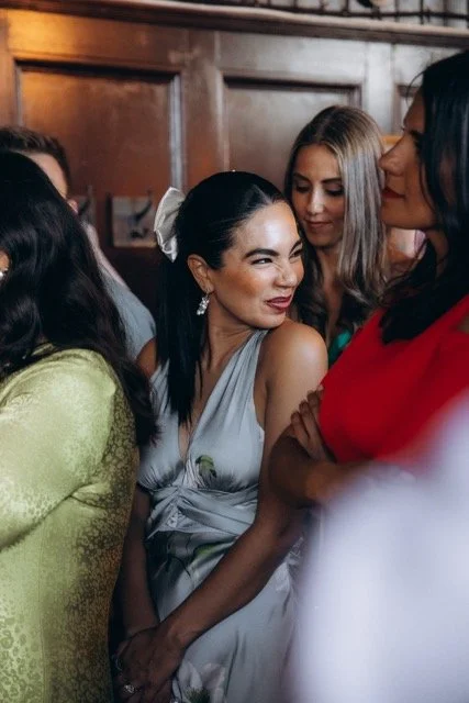  Guests laughing together with the bride at a London wedding reception — candid documentary photography capturing genuine emotion and connection 
