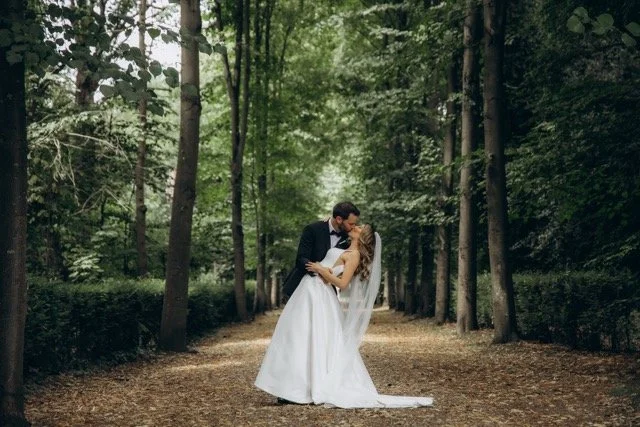 Bride and groom sharing a kiss at the end of a tall tree-lined avenue in chiswick park