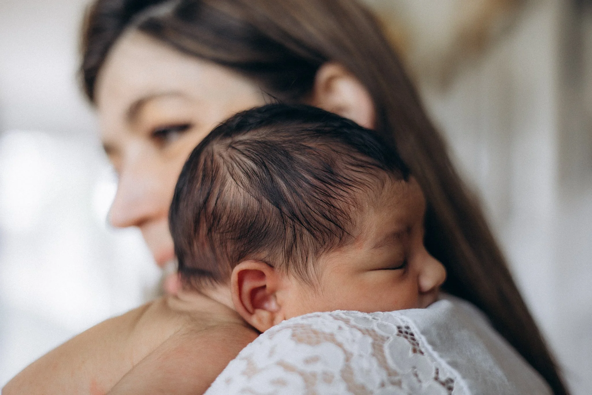 Mother holding her sleeping newborn, candid family photography London