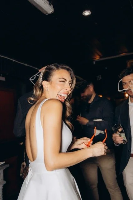 Bride laughing while champagne is sprayed on the dance floor
