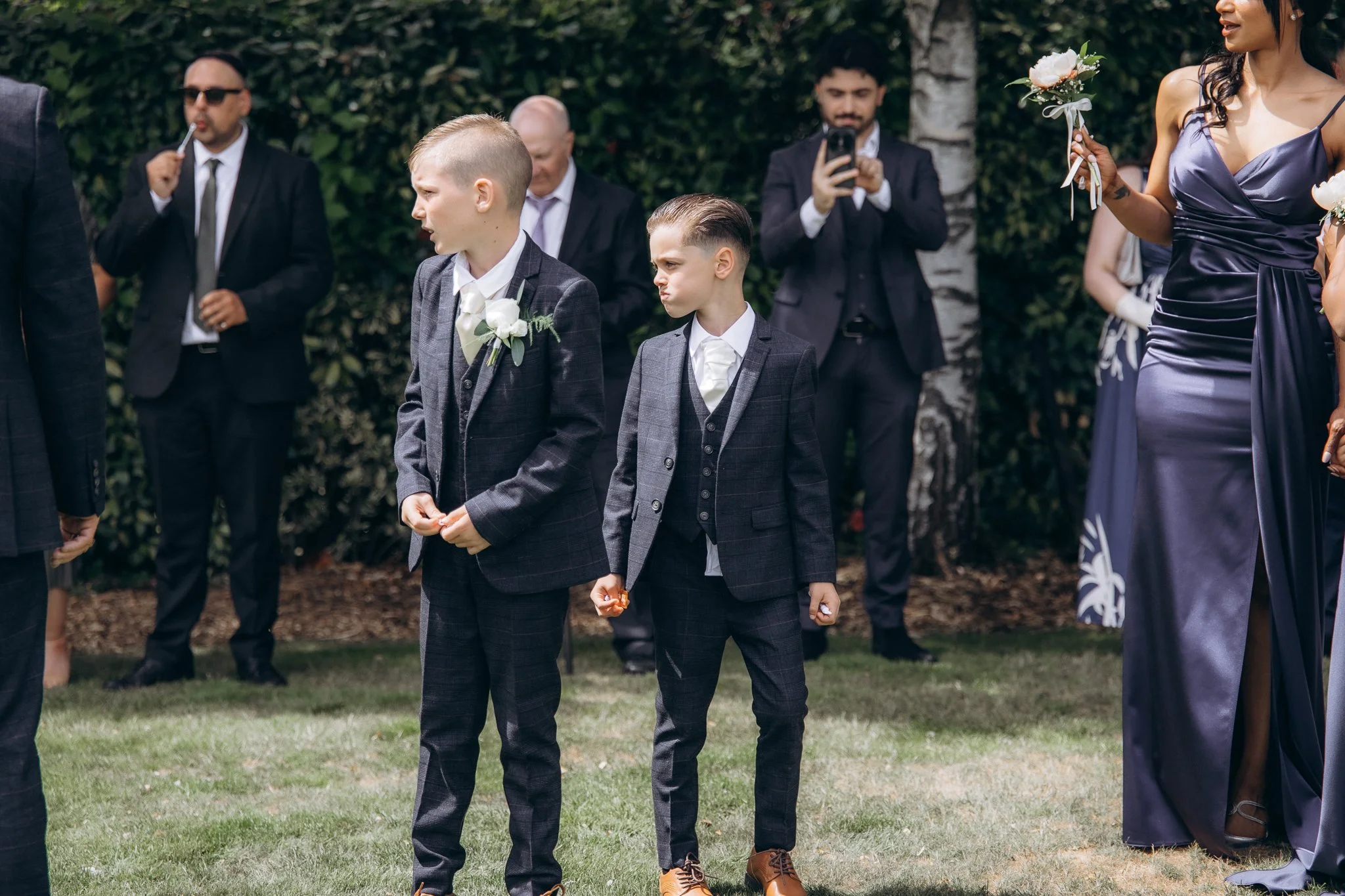 Two young page boys walking down the outdoor aisle