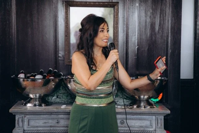 Bridesmaid speaking into a microphone during a speech, standing beside a mirror
