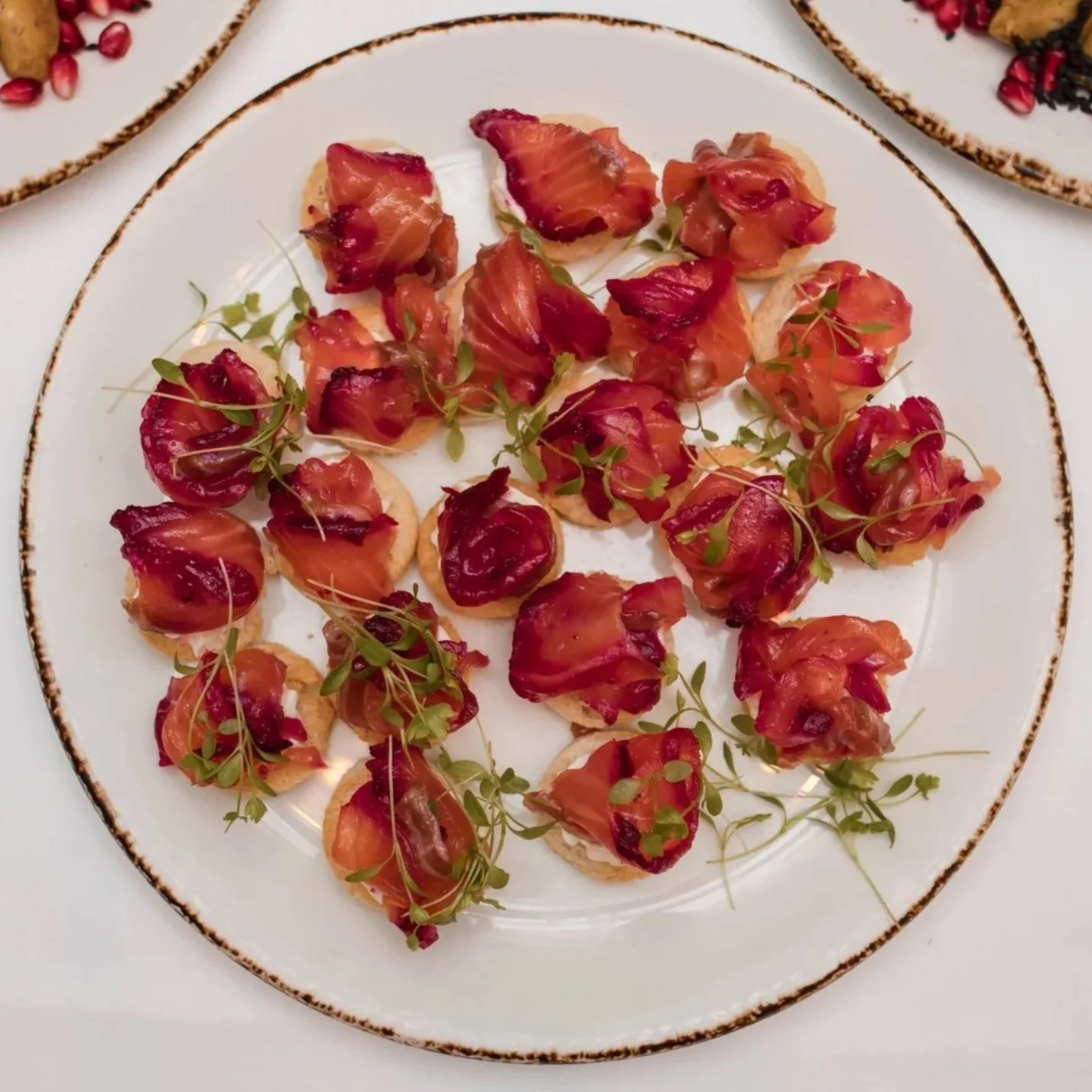 Plate of canapé bites topped with smoked salmon and microgreens.