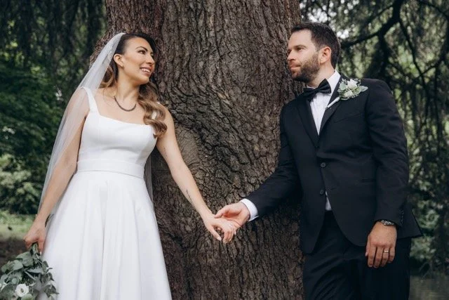 Bride and groom holding hands and walking, bride looking over her shoulder