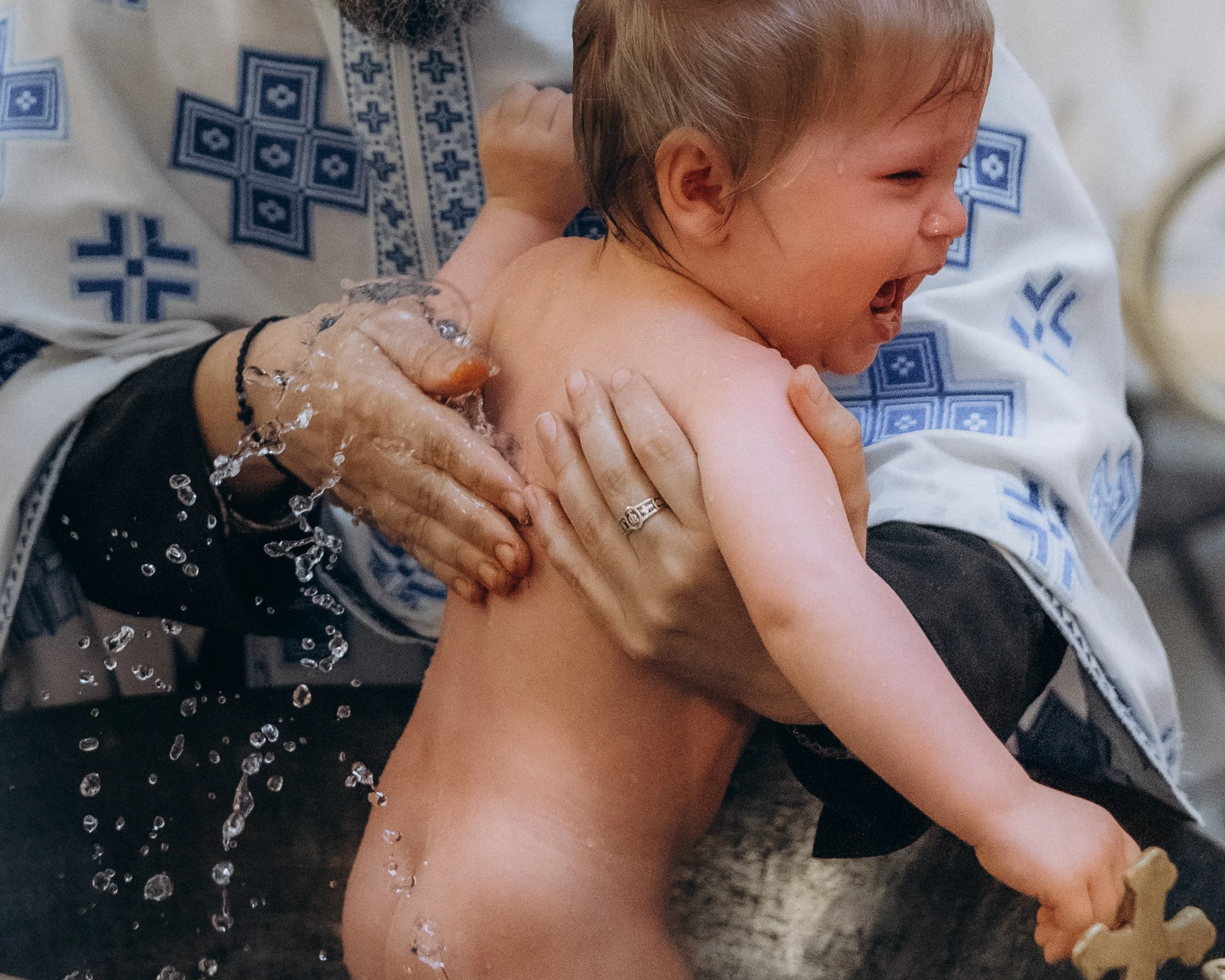 Baby during the baptism water ceremony, candid christening photography London