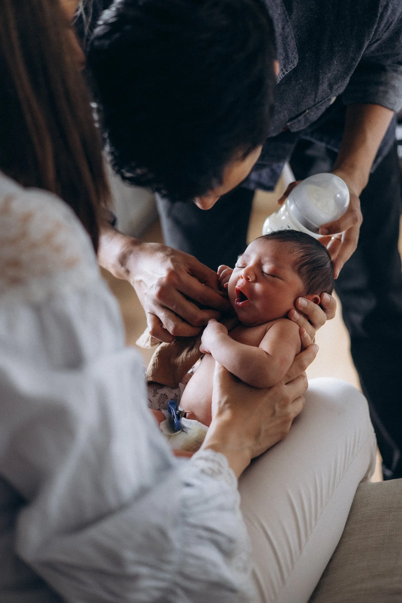 Family photography London — father feeding newborn while mother looks on