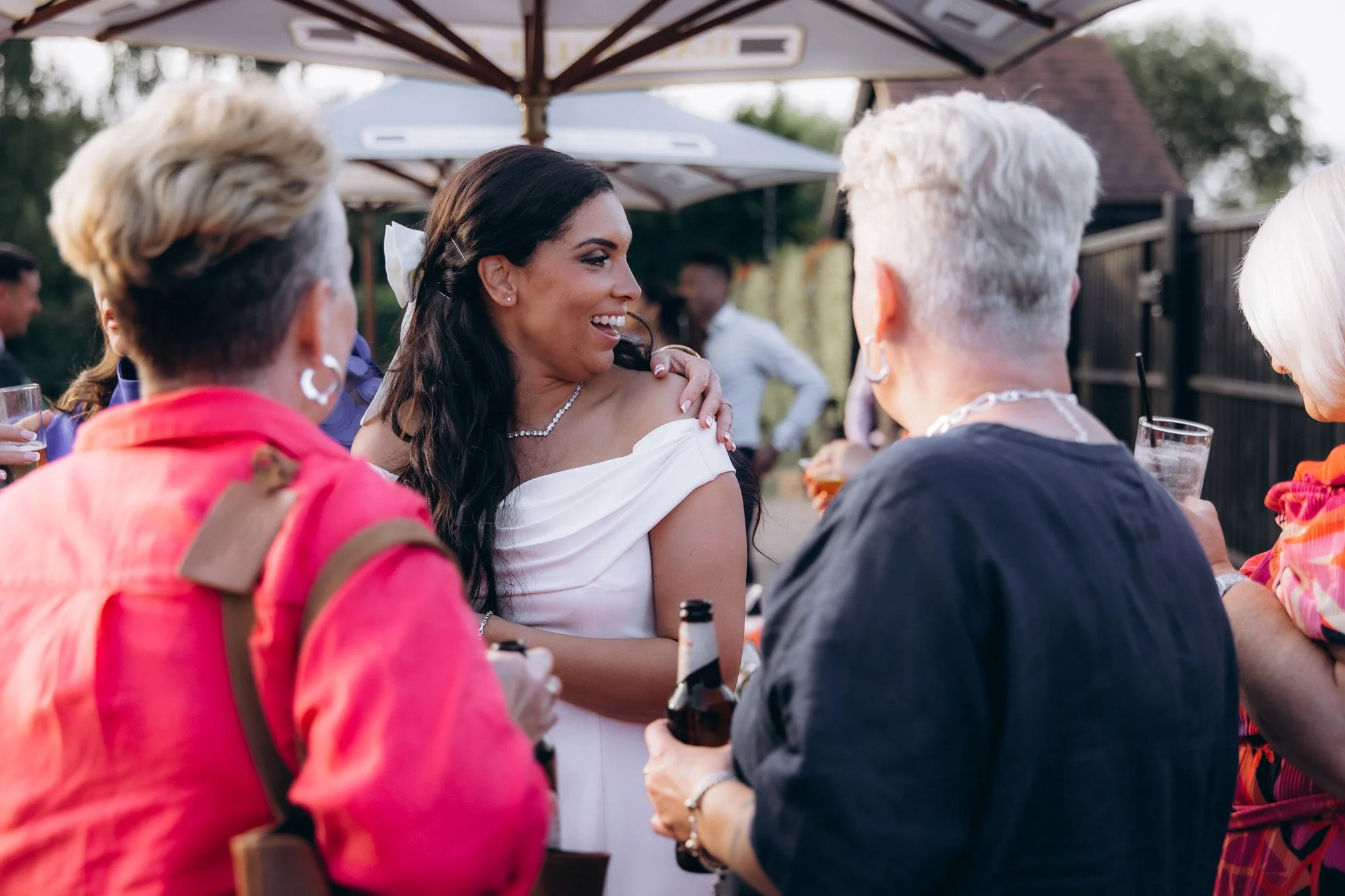 Bride chatting with an older guest outdoors, drinks in hand