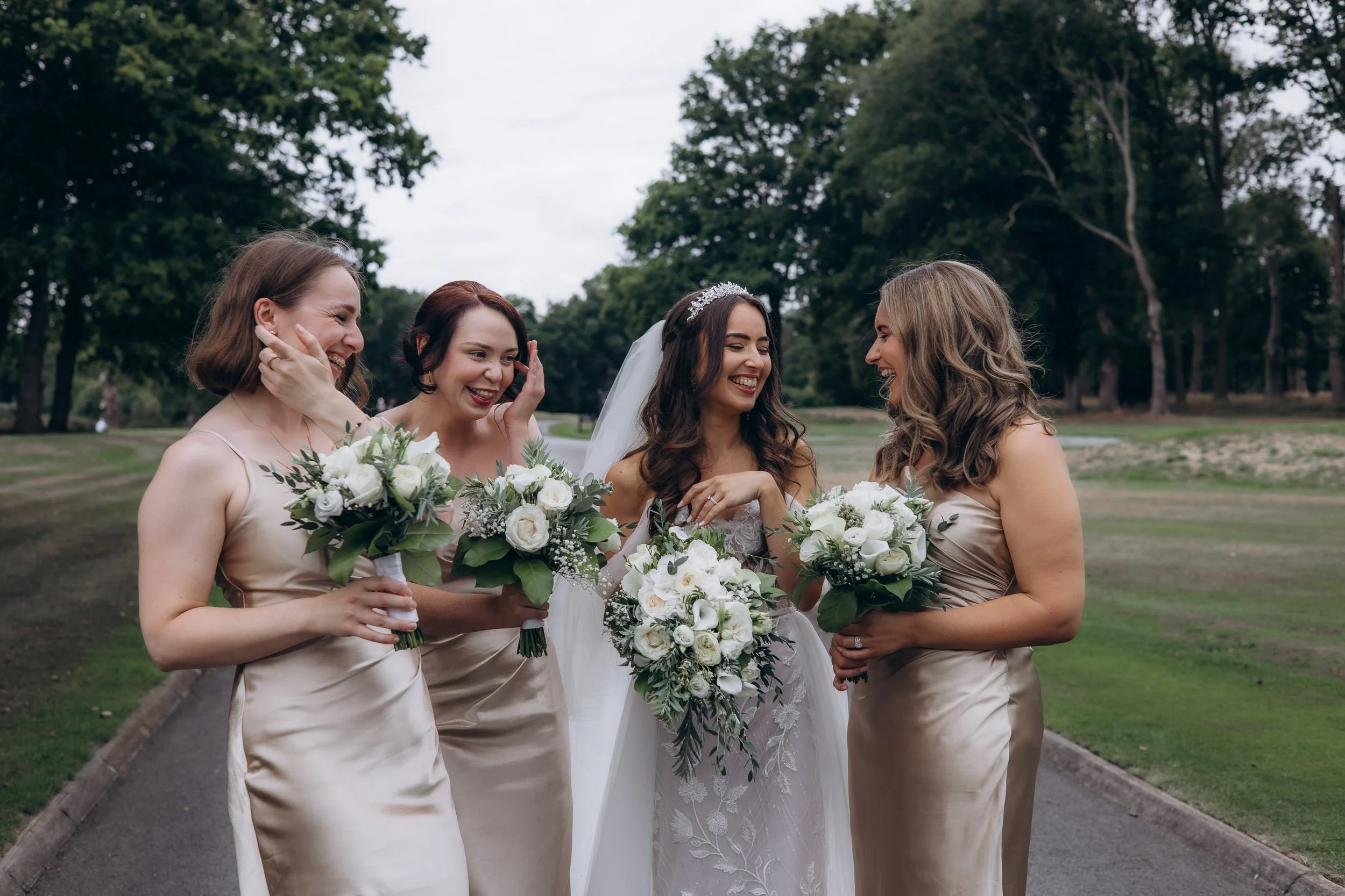 A relaxed and candid photo of bridesmaids in champagne silk dresses laughing together during a London summer wedding.