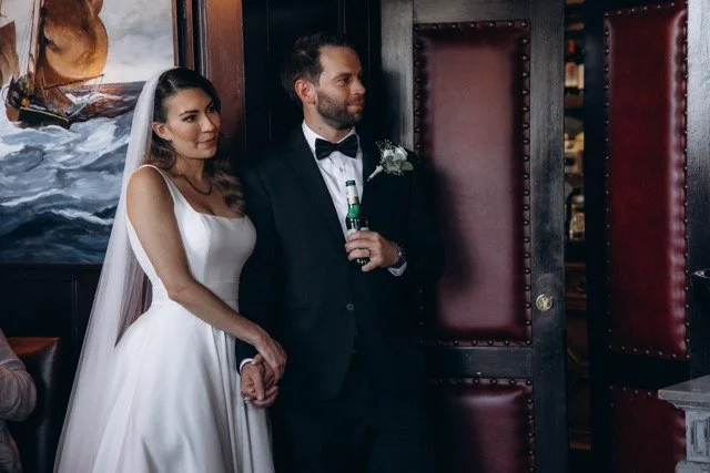 Bride and groom standing together and smiling in a warmly lit reception room
