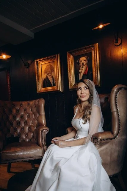 Bride seated in a leather armchair in a moody, warmly lit room at The Old Ship pub