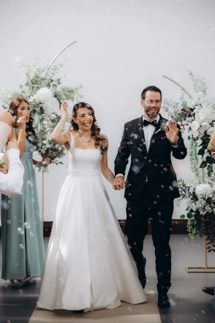 Bride and groom laughing and walking through a shower of bubbles 