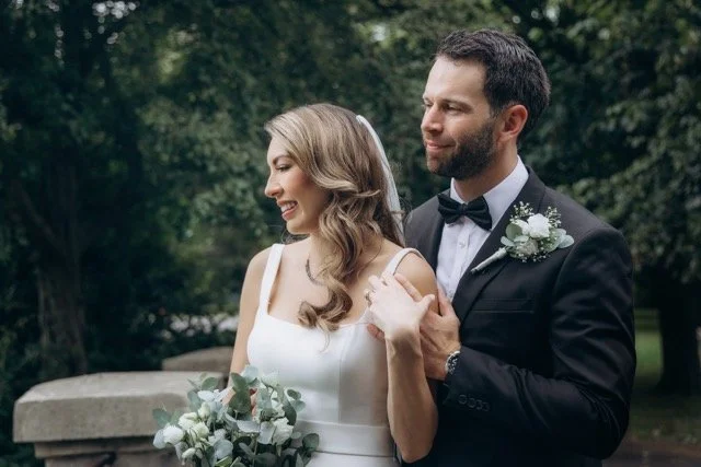Bride and groom portrait holding hands and smiling at each other outdoors