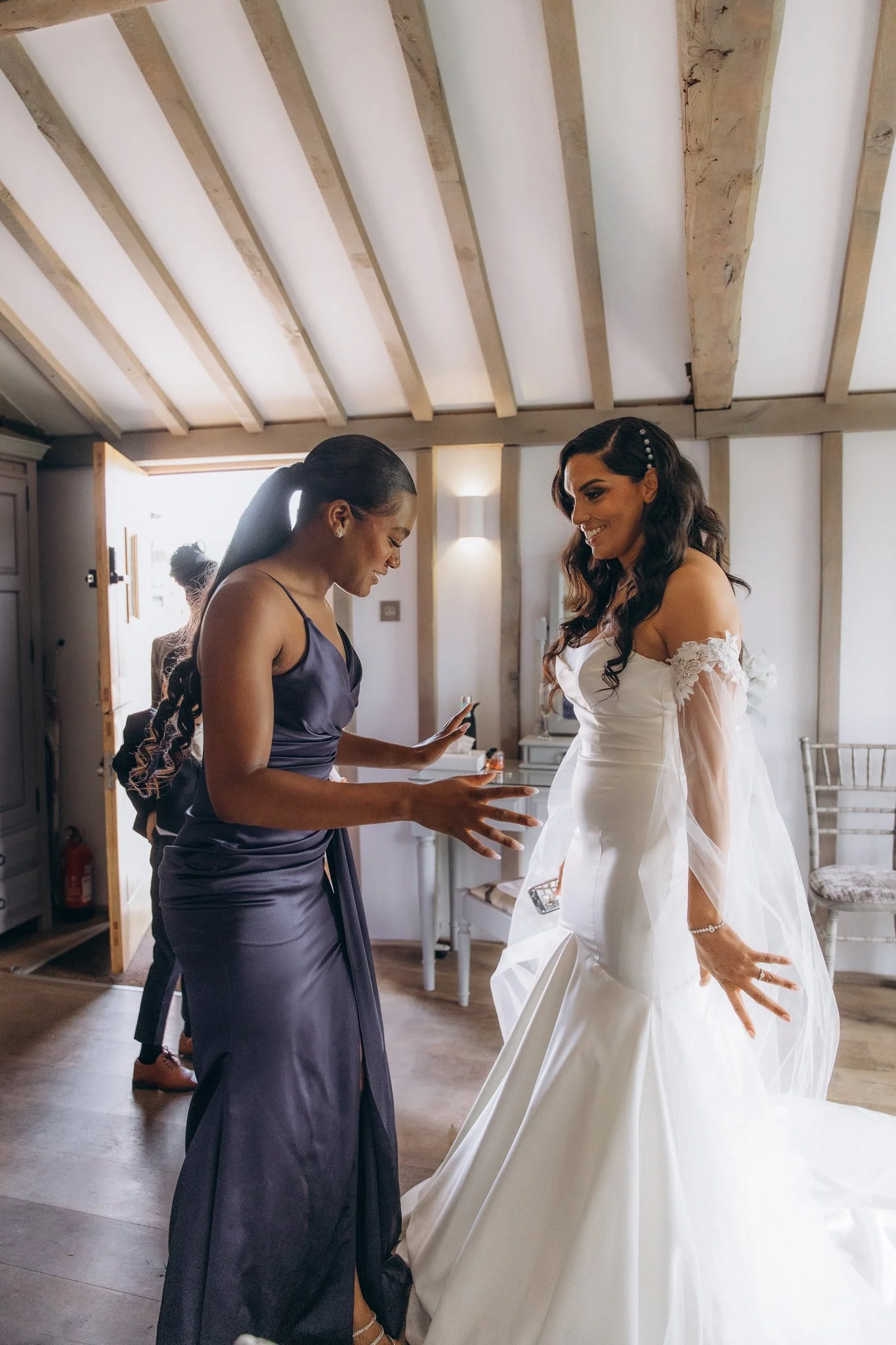 Two bridesmaids laughing together indoors before the ceremony