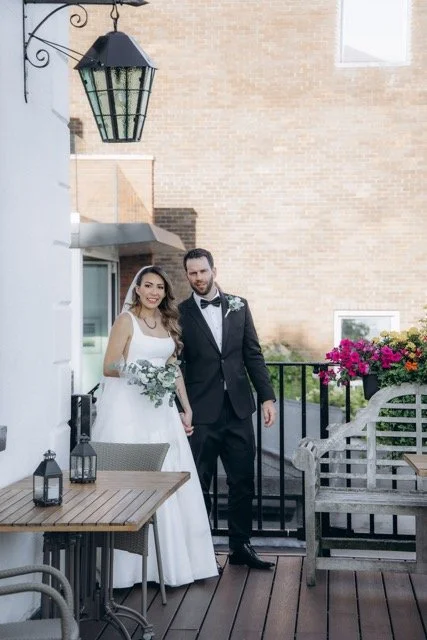 Bride and groom walking hand in hand down a flower-lined entrance path