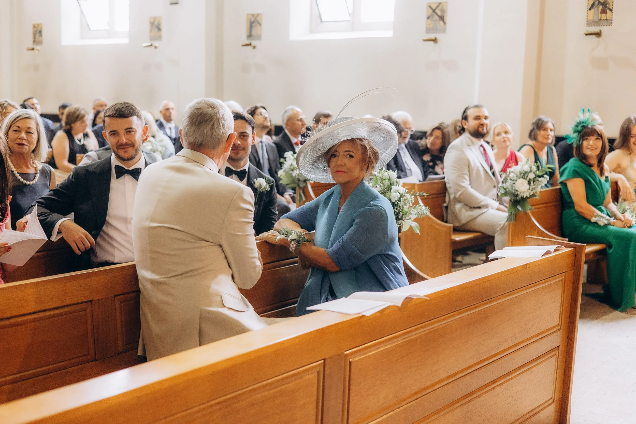 Natural documentary photography of wedding guests seated in pews during a heartfelt London church ceremony.