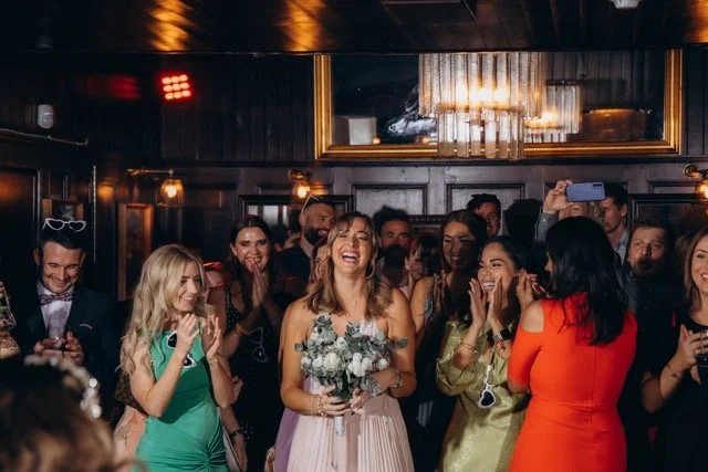 Group of female guests laughing as the bouquet is tossed