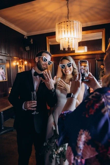 Bride and groom wearing matching heart-shaped novelty sunglasses and posing for a photo at The Old Ship