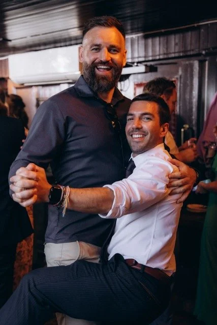 Two male guests laughing and embracing each other at the party