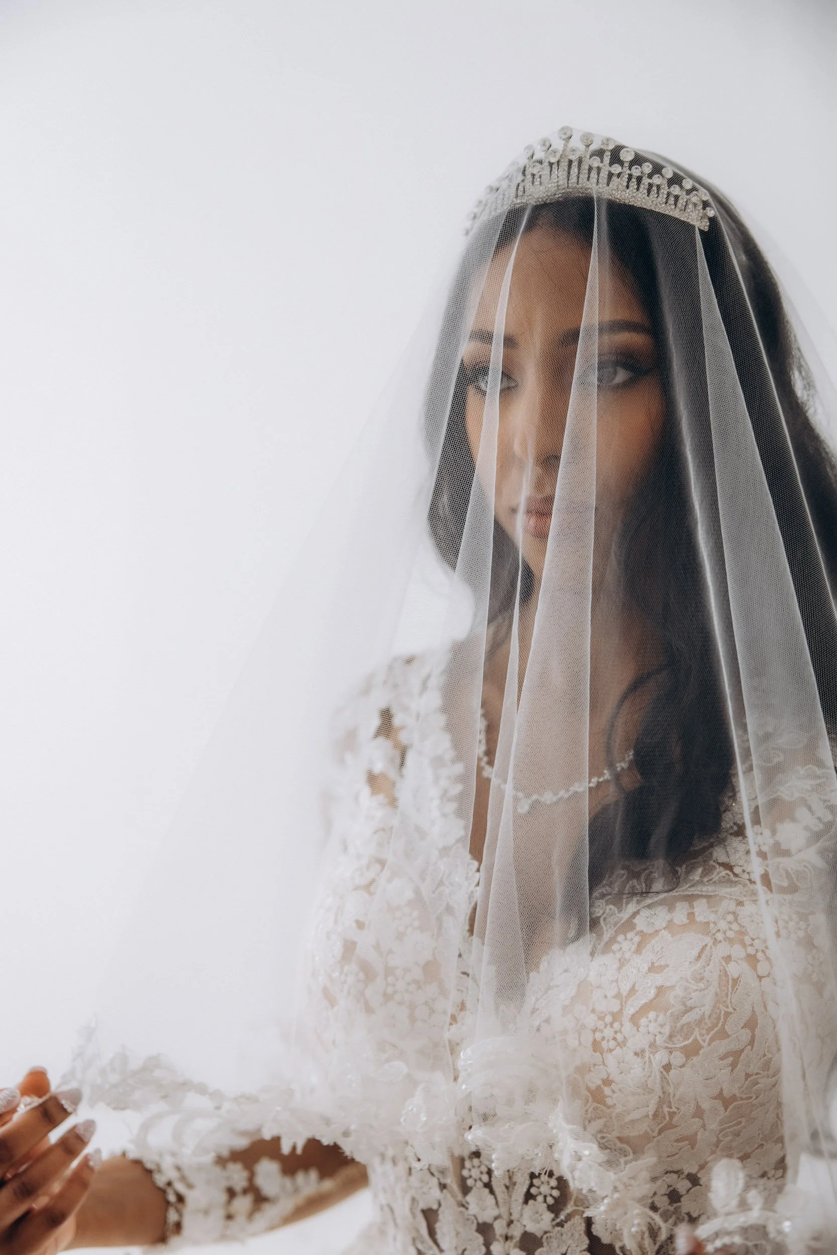 Intimate, close-up portrait of a gorgeous bride with a long, classic lace-edged wedding veil, by luxury London wedding photographer Lusy Klintsova at [Specific London Hotel]. Perfect for elegant, timeless inspiration.