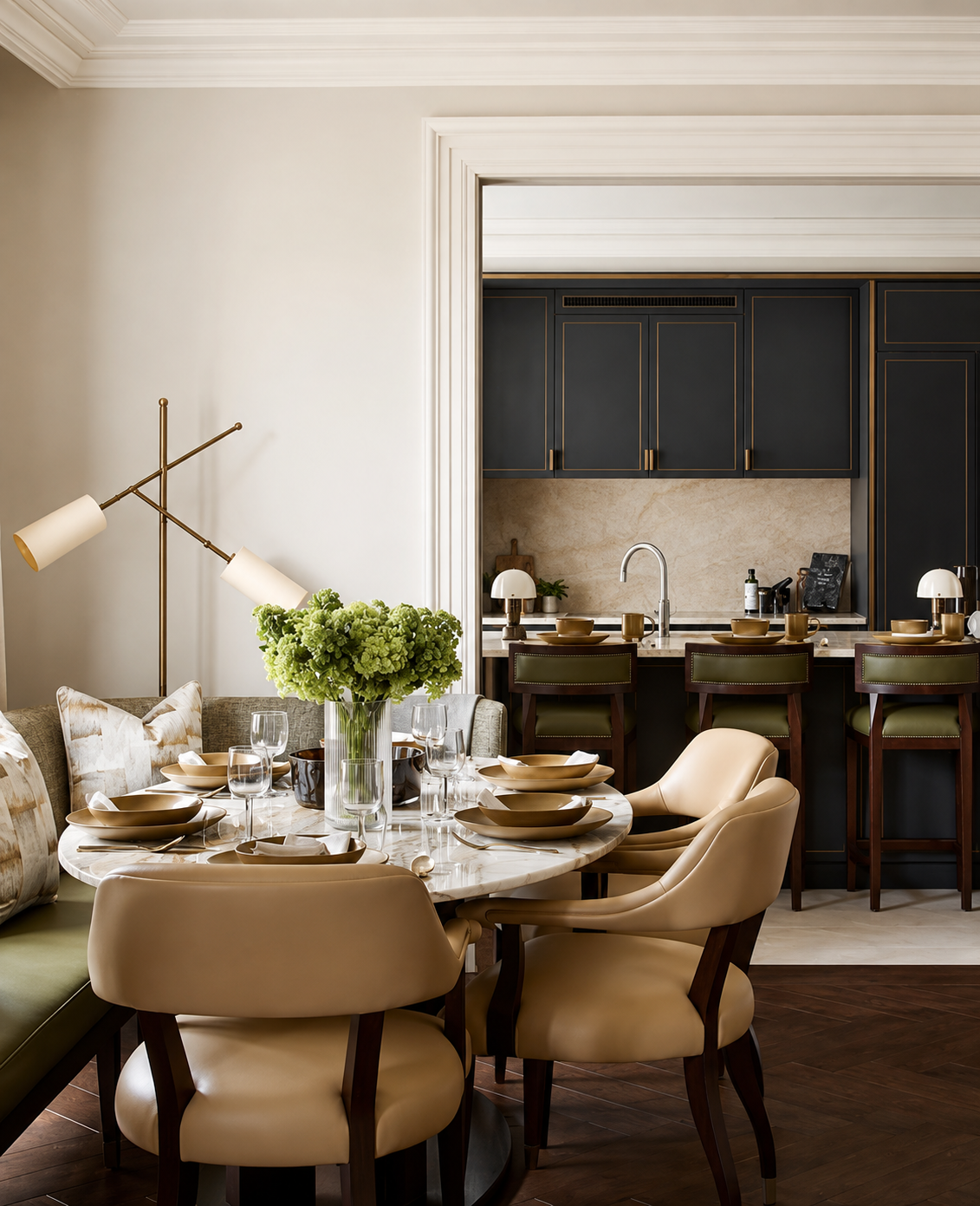 A dining table with three cream chairs and a green banquette. In the background is a kitchen with 3 green bar stools.