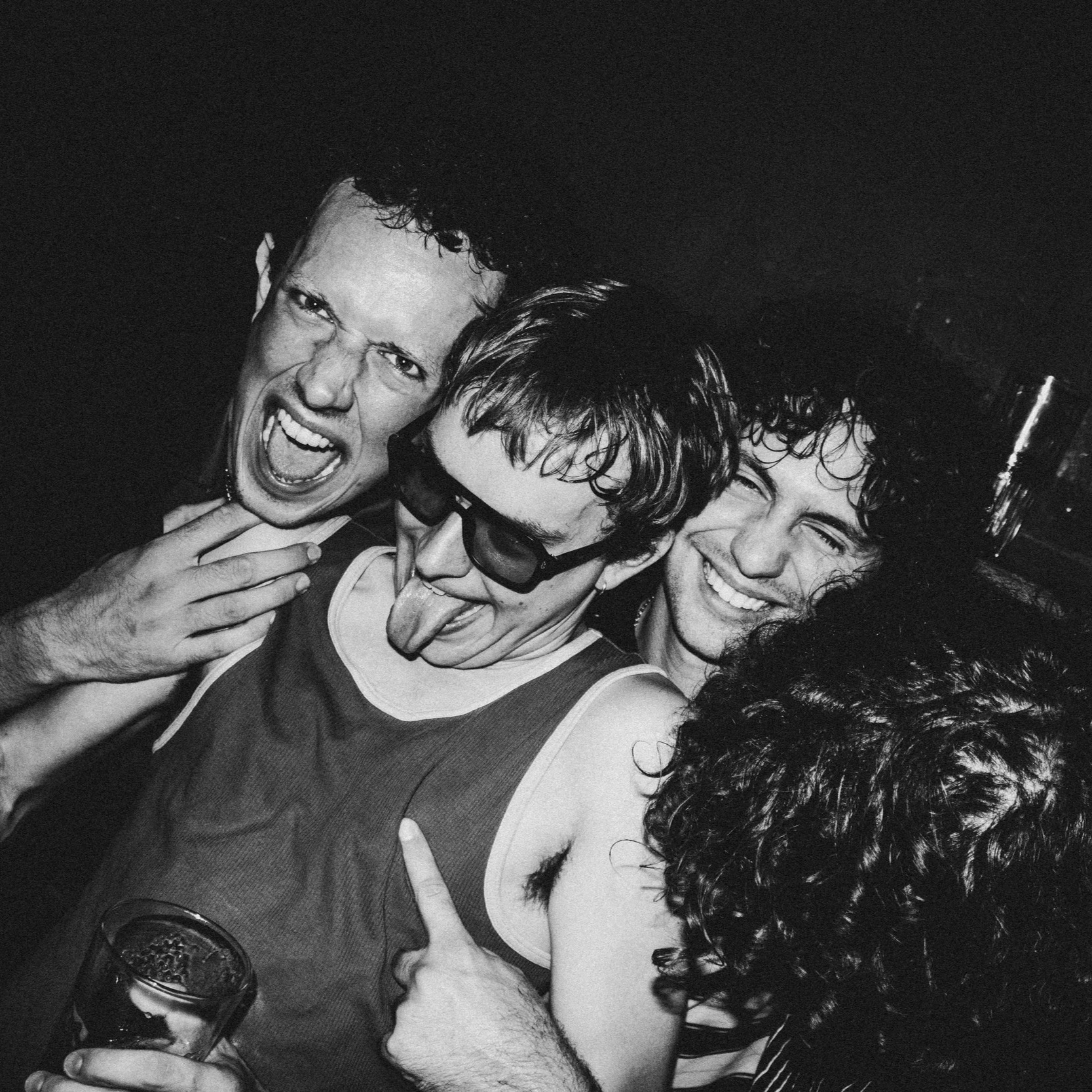 Black and white photo of four friends at a party, making funny faces and having a good time.