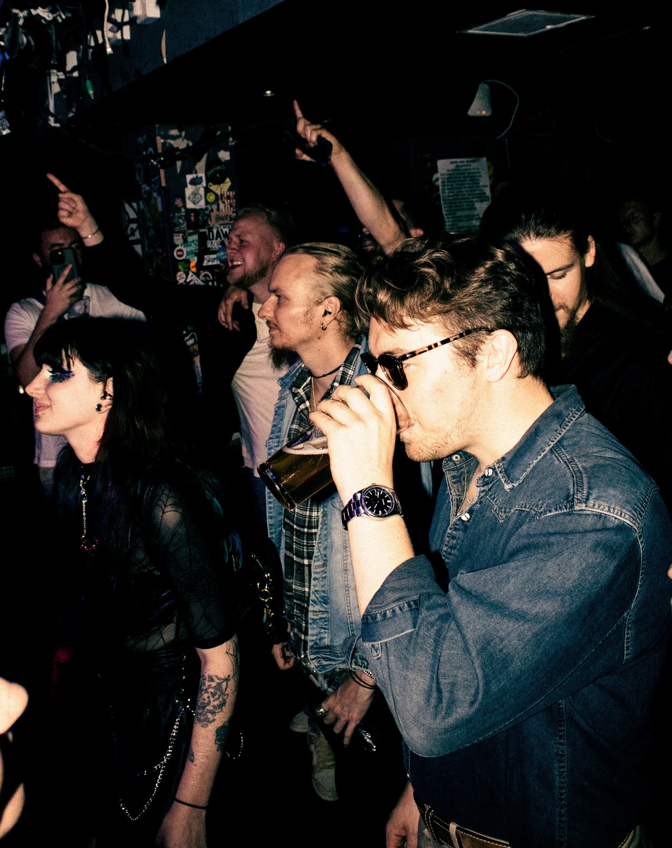 People dancing and drinking in a crowded nightclub or concert venue.