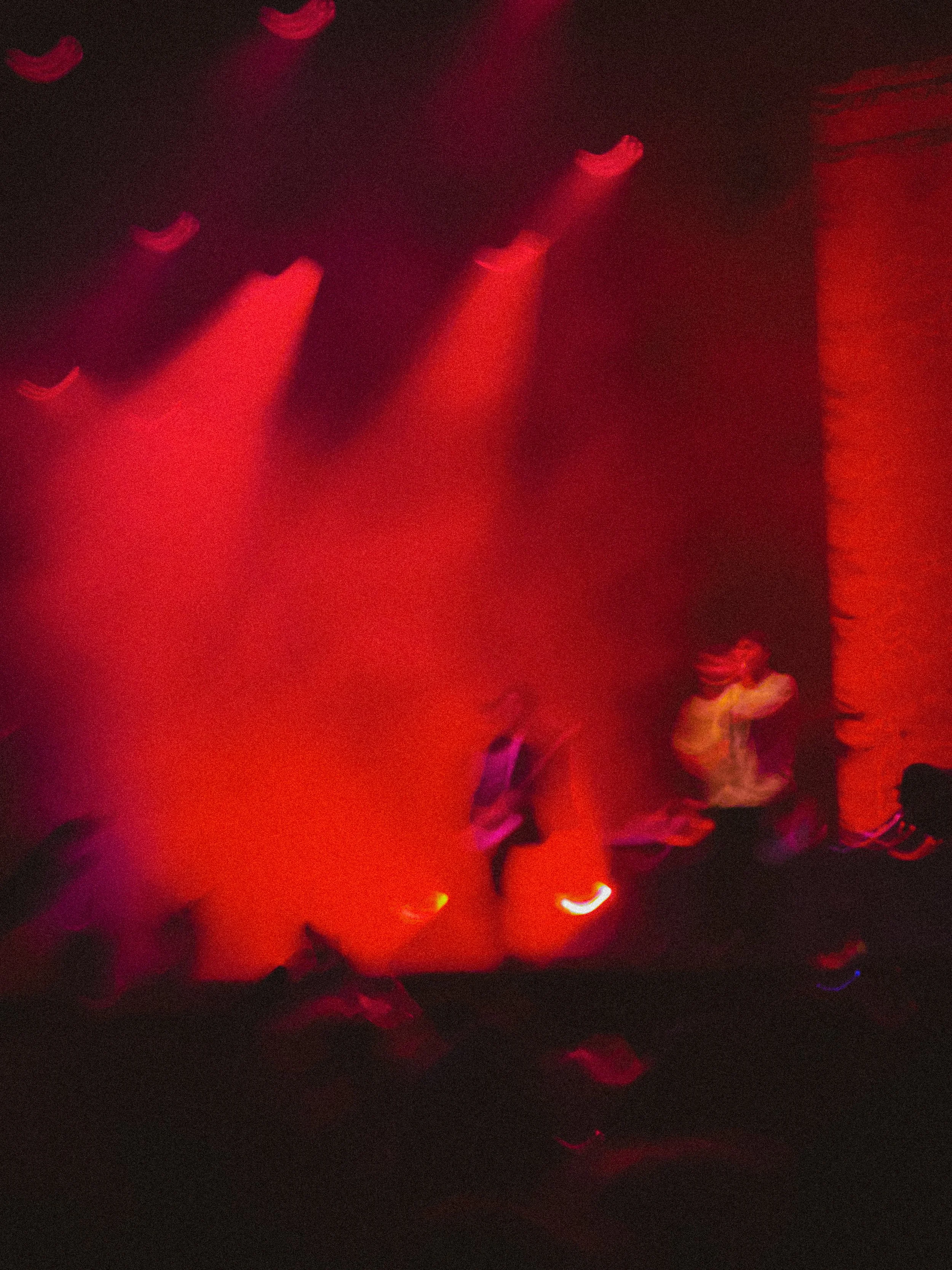 Dimly lit stage with red lighting, showing two blurry figures. Nothing But Thieves at Truck Festival 2025