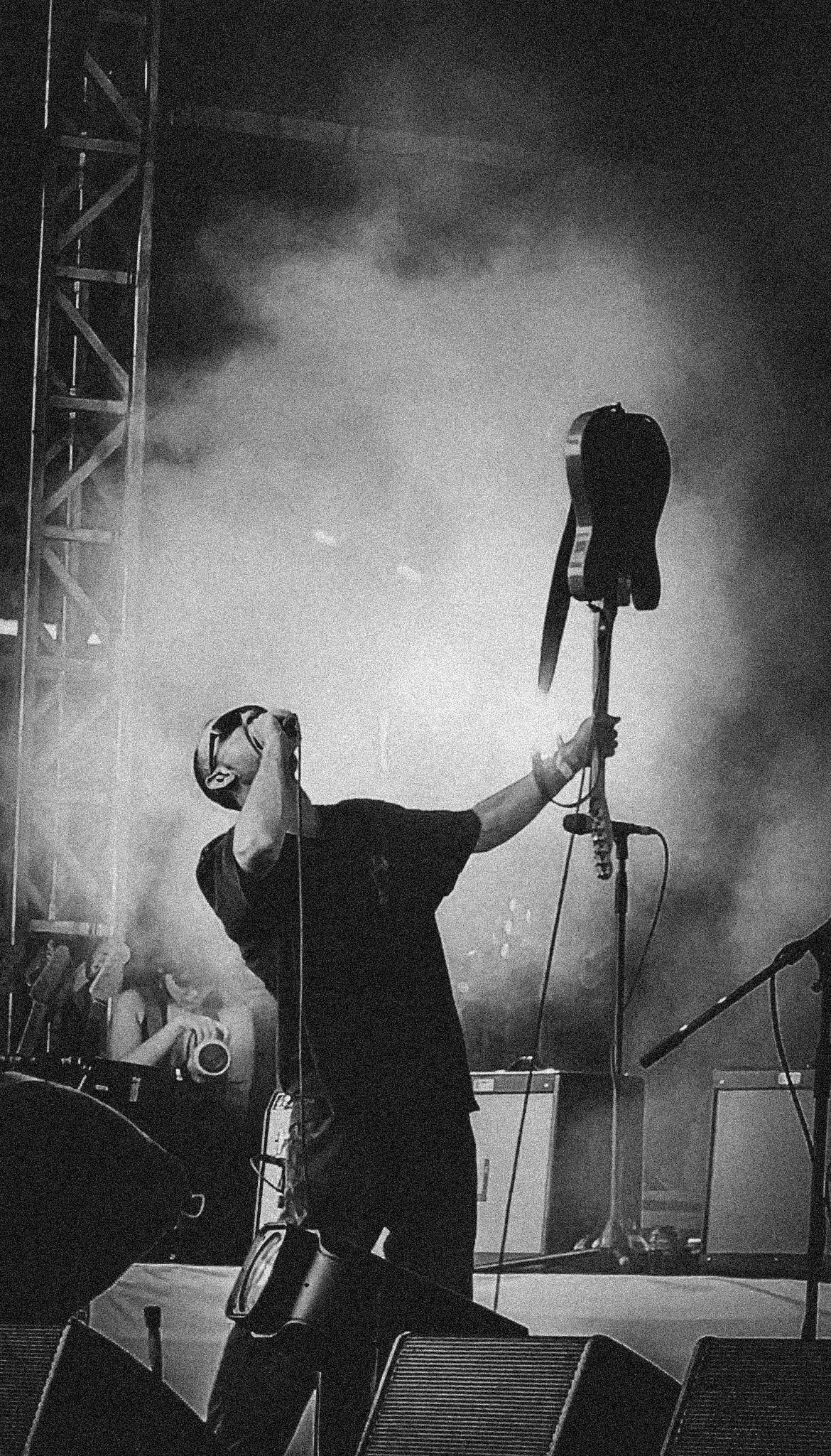 A person on stage holding a guitar, with stage equipment and fog in the background. Wunderhorse, Jacob Slater, Truck Festival in 2025.