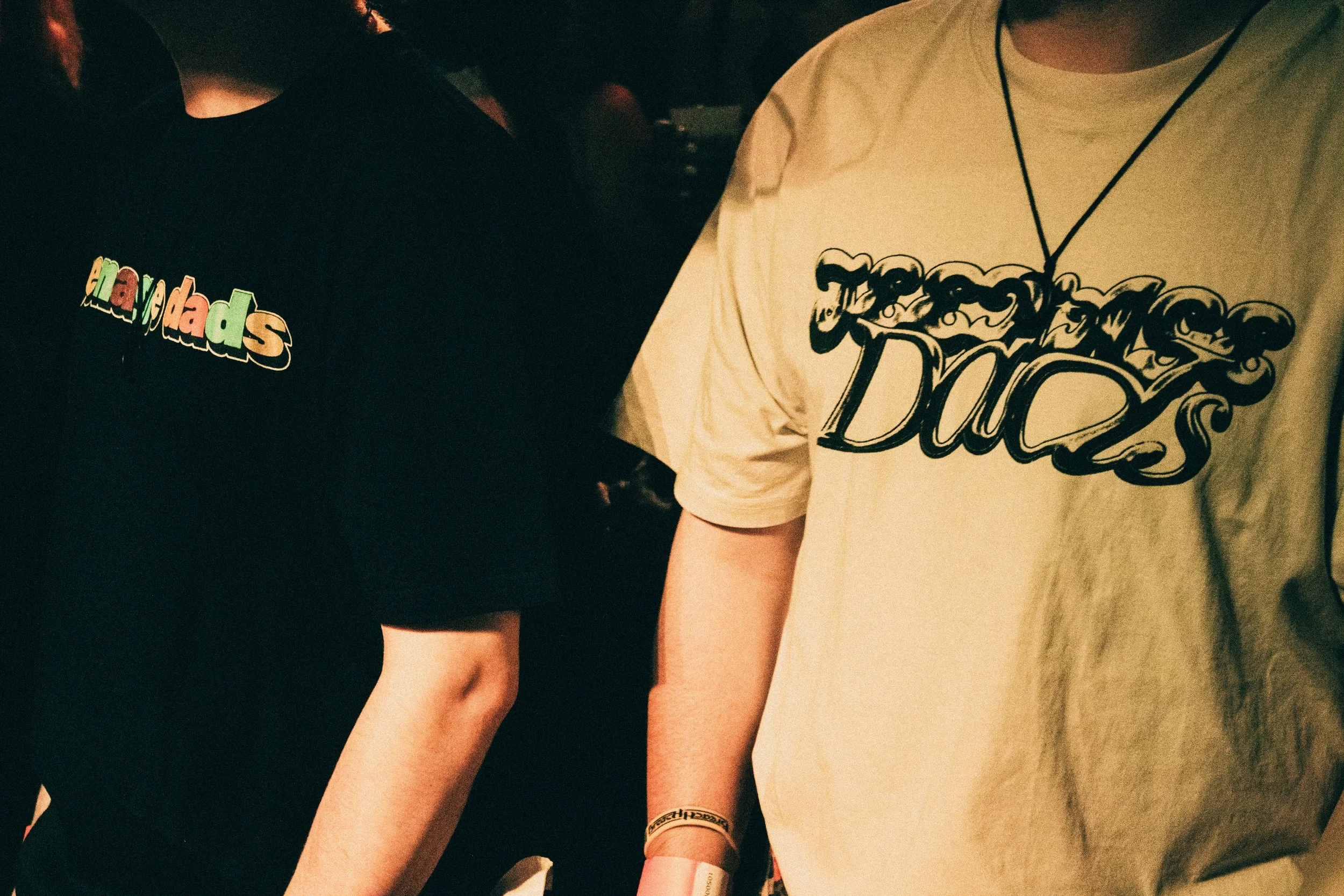 People wearing T-shirts with the words Teenage Dads on them at a social gathering or event.