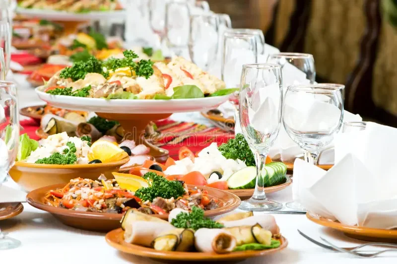 A table set with various plates of food, including salads and appetizers, along with empty wine glasses and silverware.