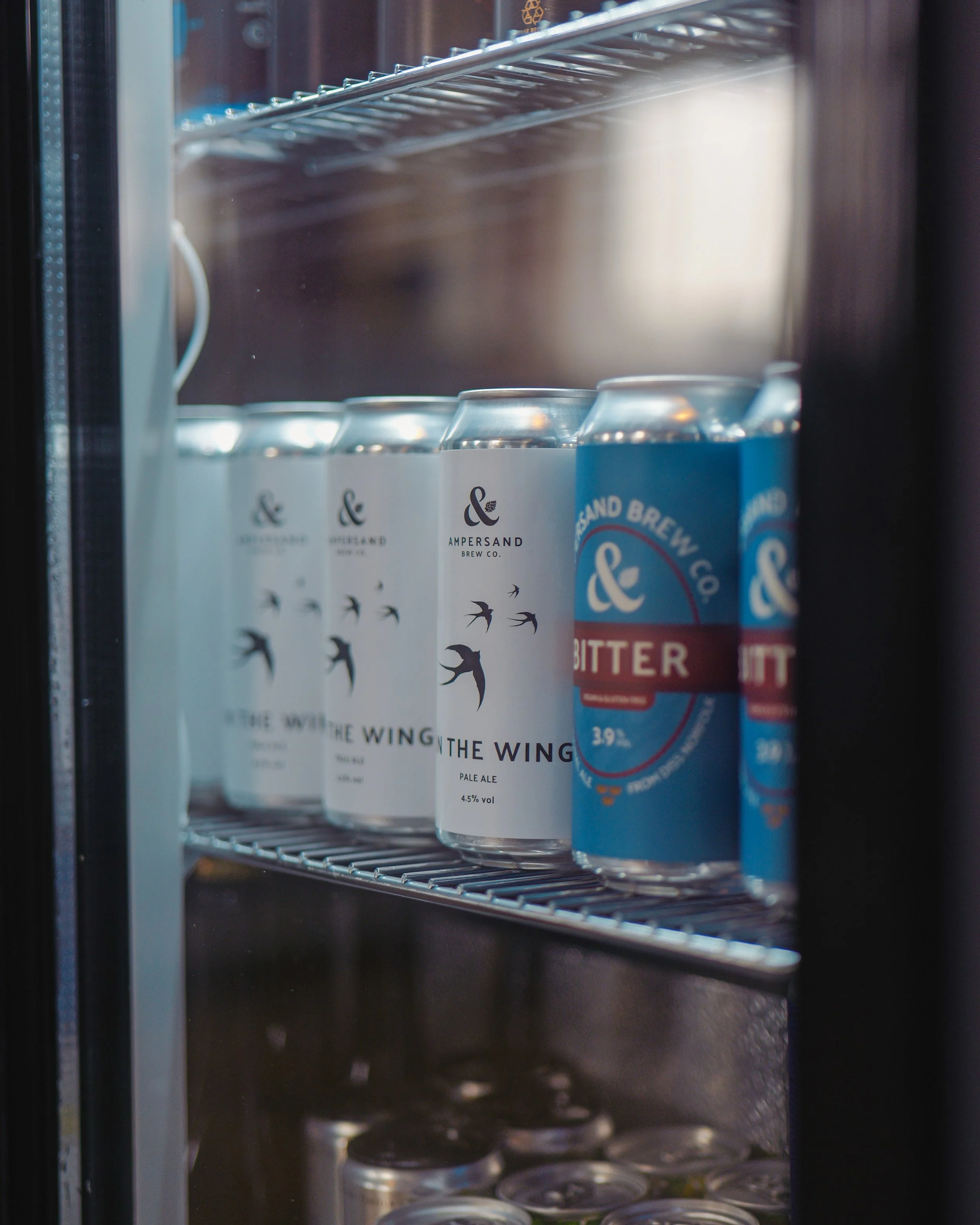 Cans of beer and bitter soda on a refrigerator shelf.