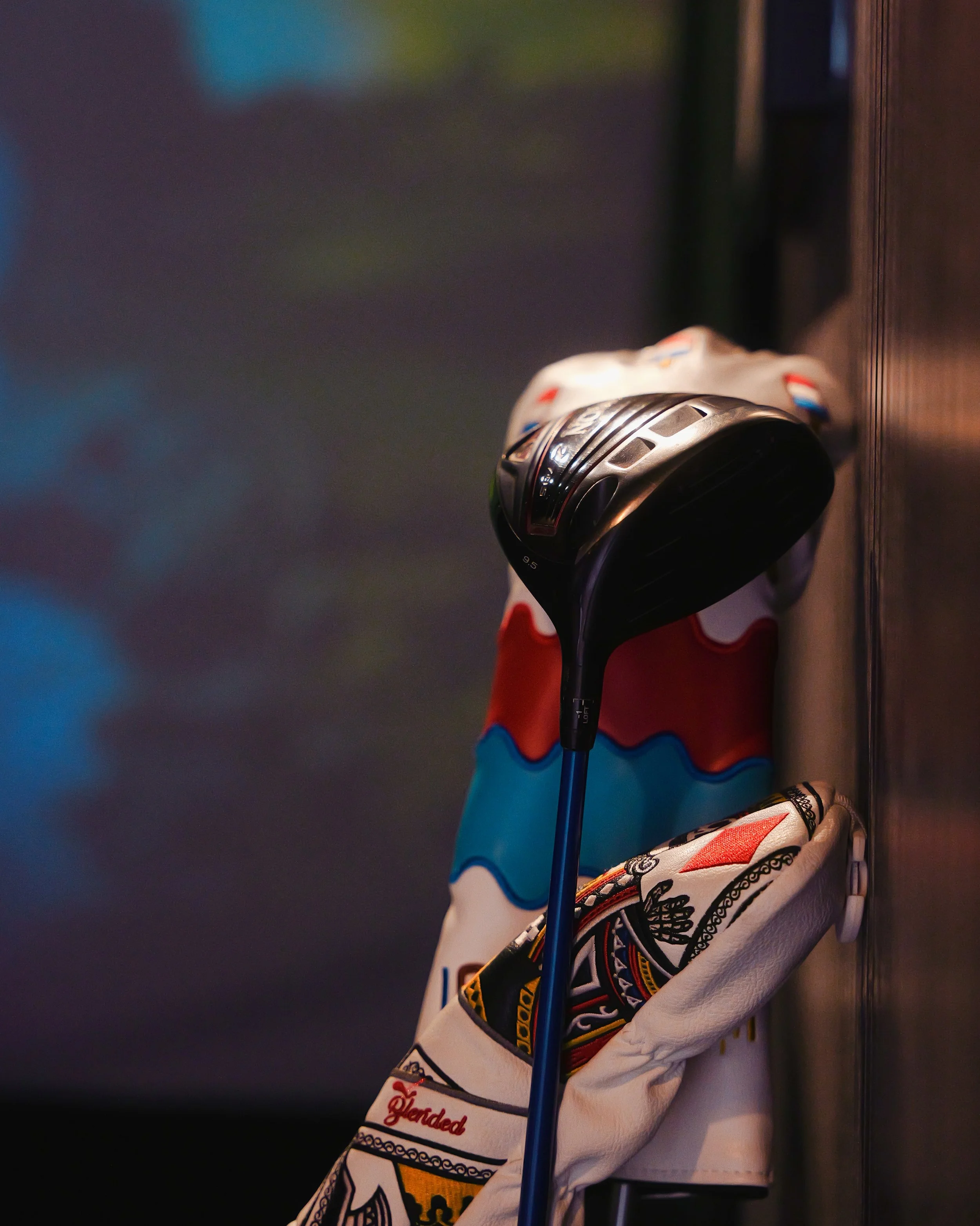 A golf club resting in a decorated golf bag against a dark, blurred background.