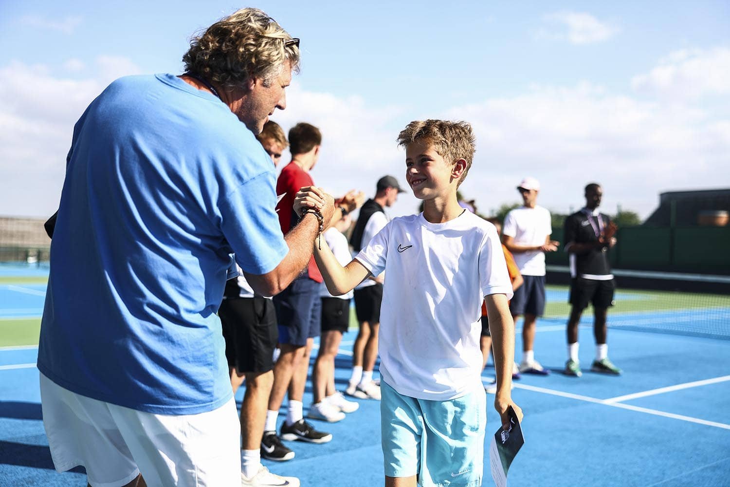 Entraîneur de tennis félicitant un joueur lors d'une cérémonie de remise de prix