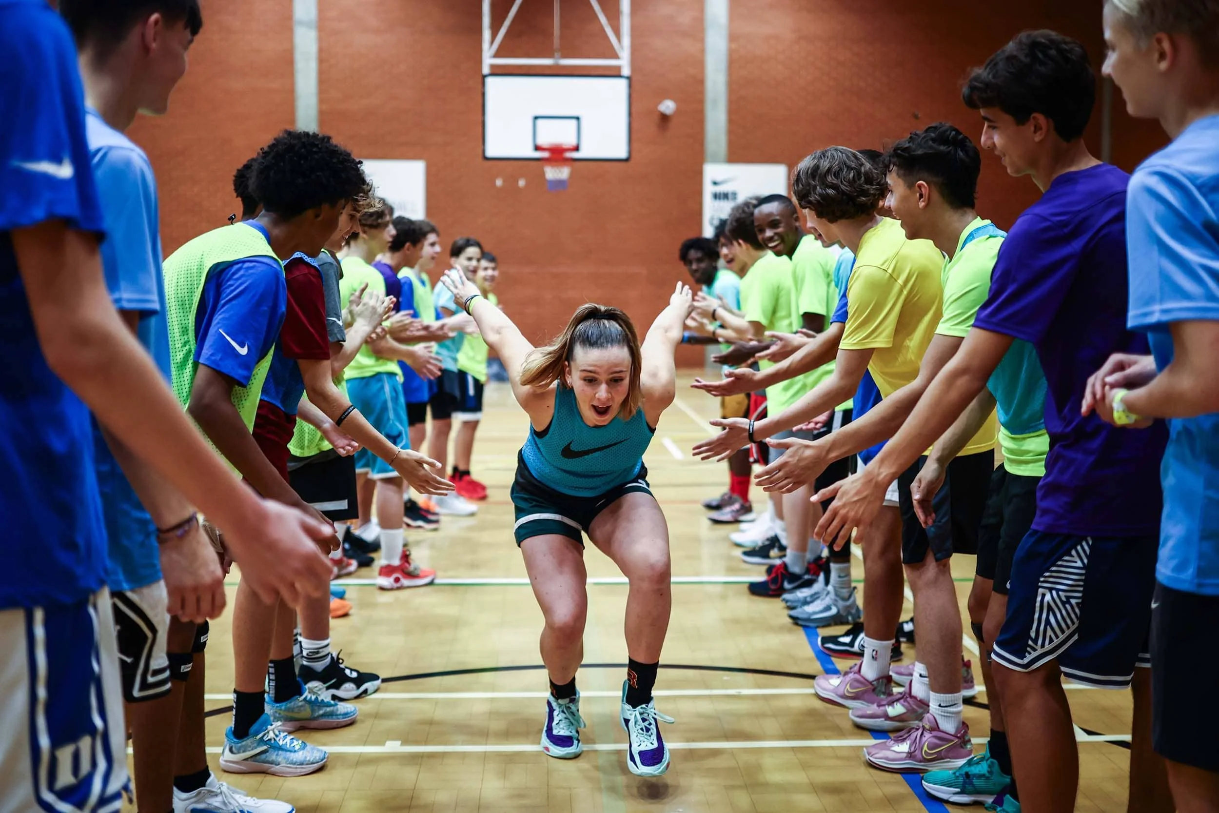 Chica chocando los cinco con sus compañeras de baloncesto en un campamento de verano.