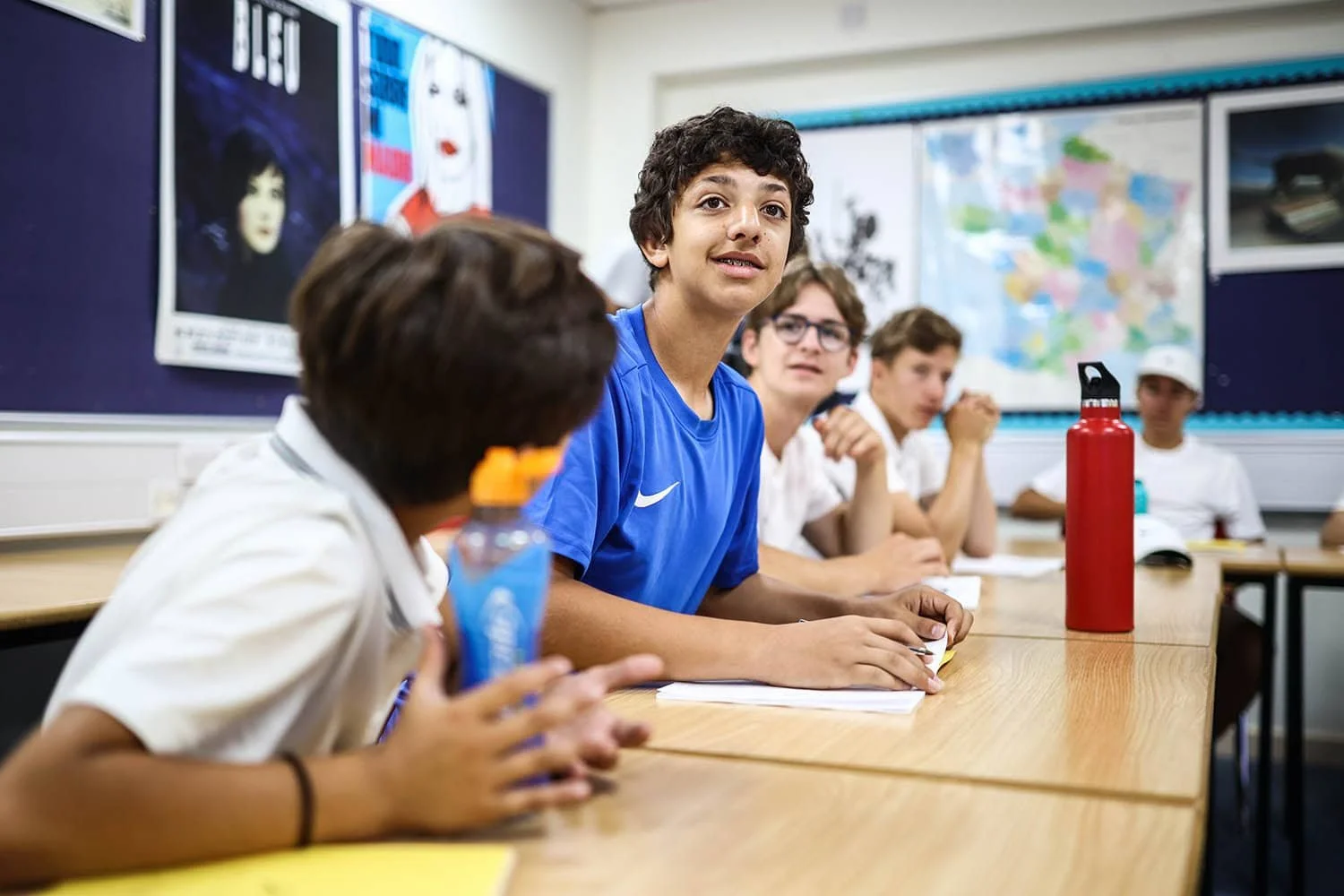 Student in EFL class leaning forward to speak to teacher