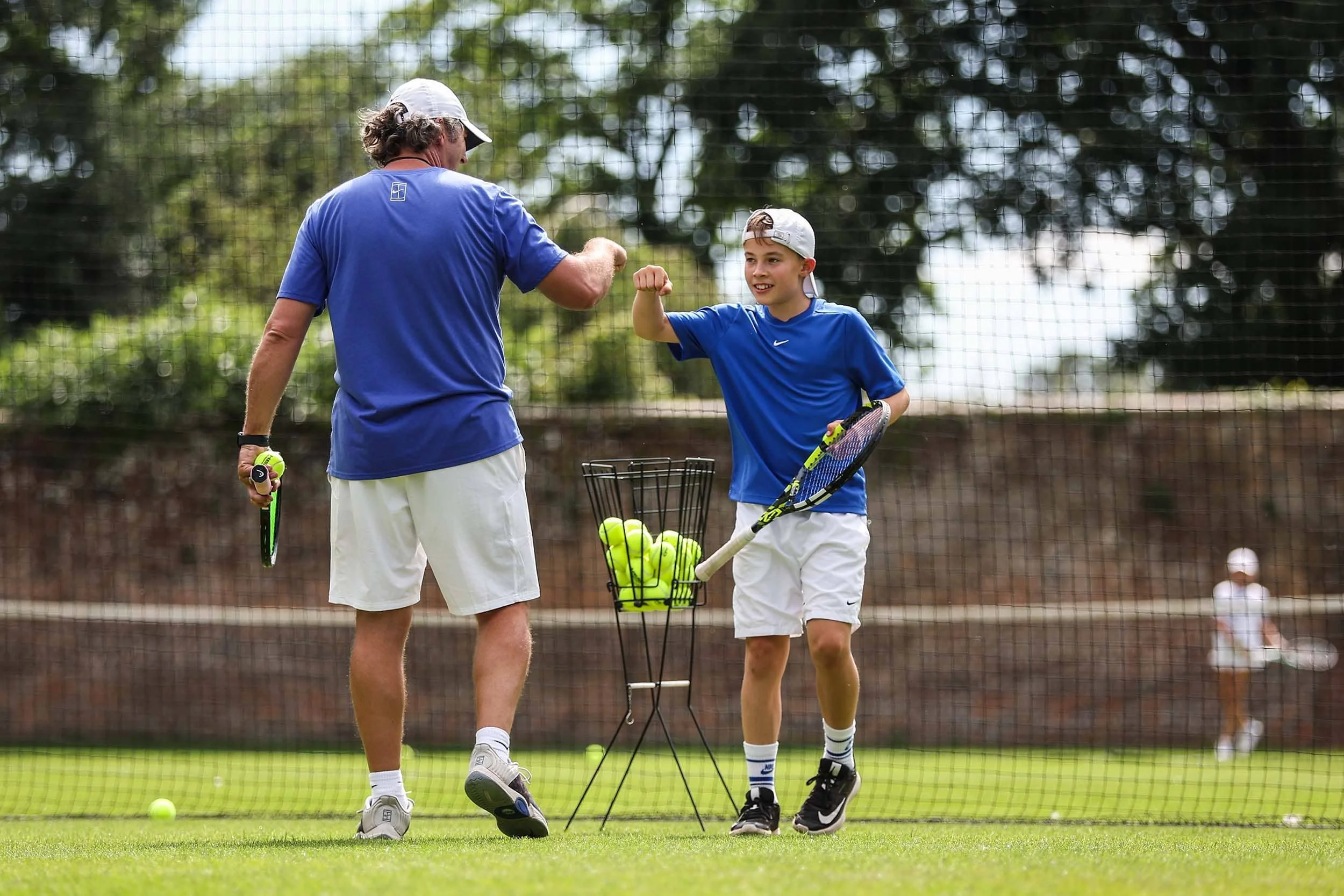 Junge und Tennistrainer stoßen mit den Fäusten aneinander