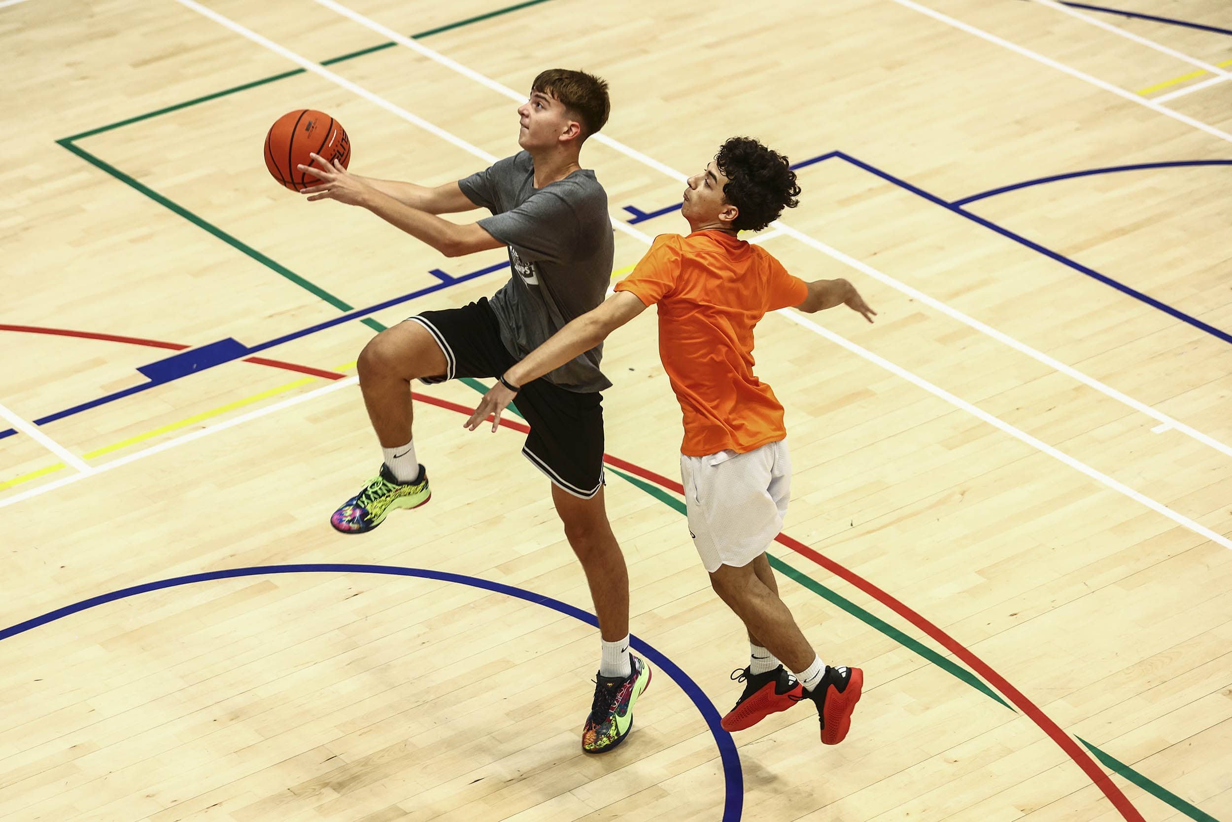Basketballspieler springt zum Wurf, während Verteidiger den Korb schützt