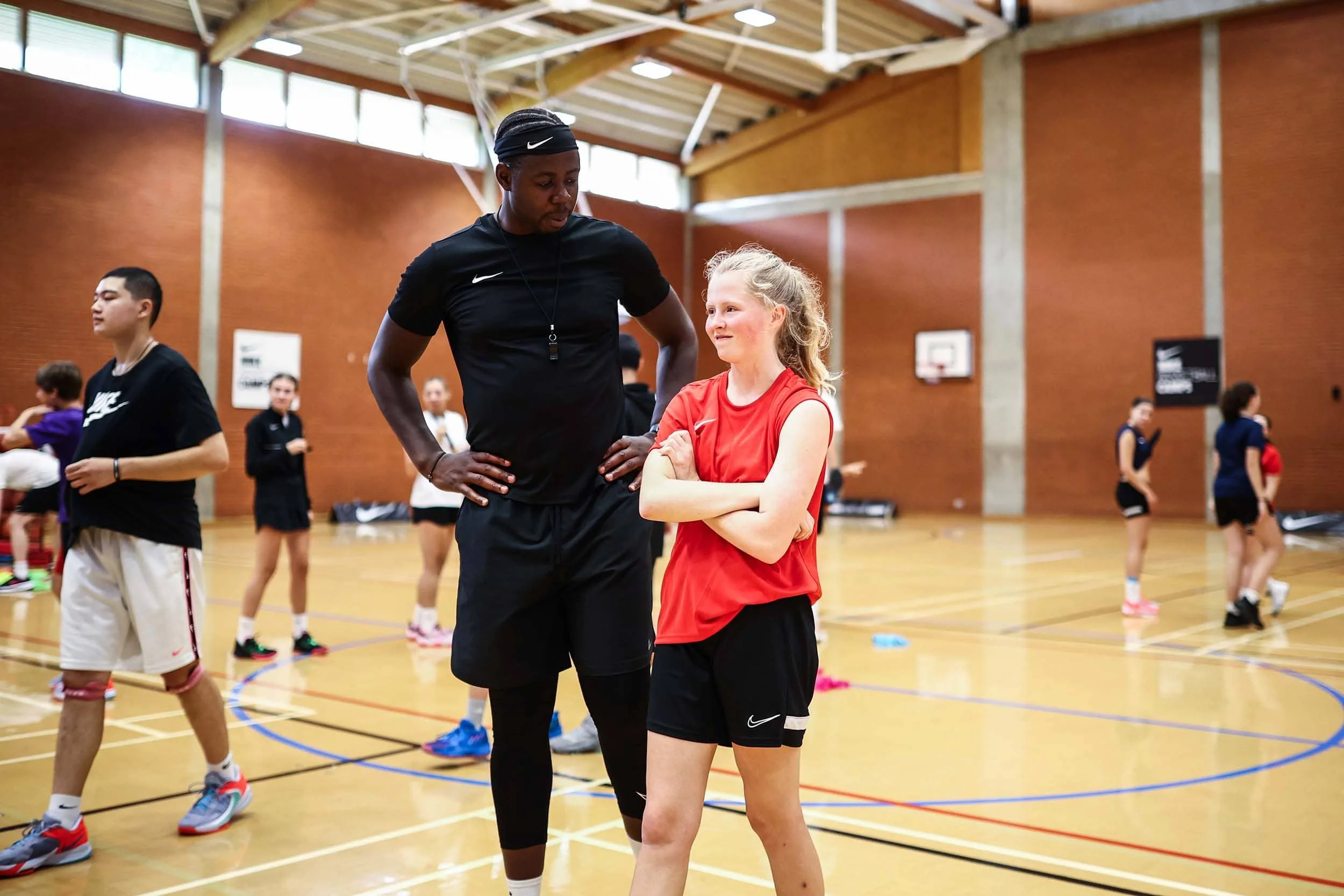 Eric Boateng, entrenador de baloncesto, hablando con una niña durante el entrenamiento.