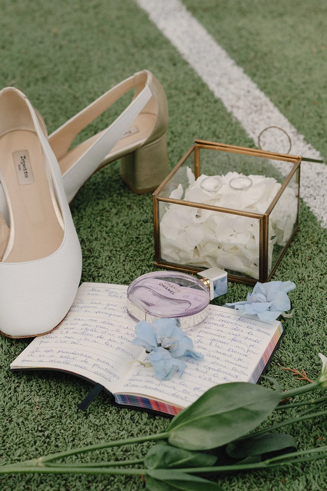 Photo détails mariage sur terrain de tennis : chaussures de la mariée, alliances, carnet de voeux, couleur des fleurs, parfum.