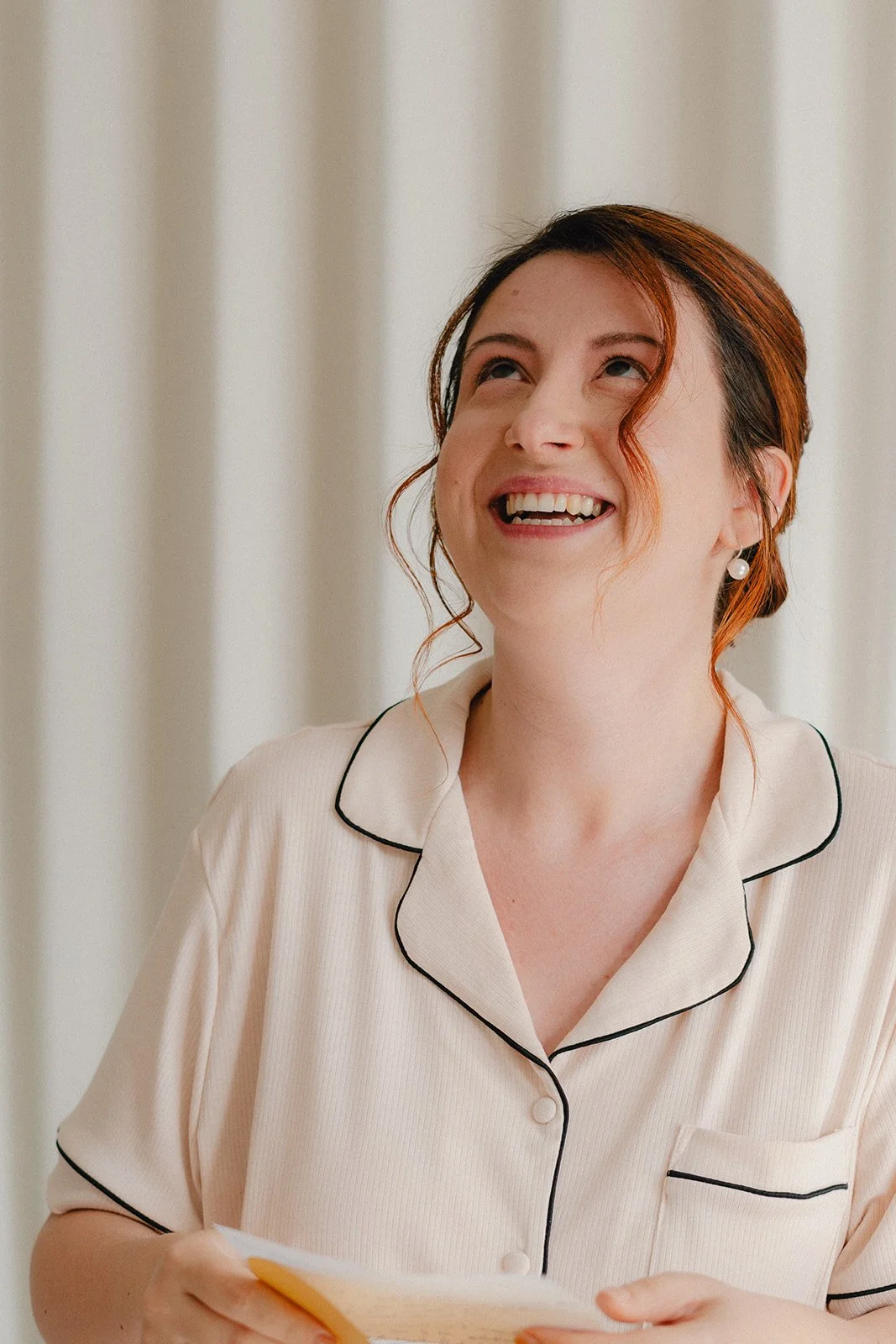 Future mariée lisant le mot de son époux avec beaucoup d'émotion, regard vers le haut pour éviter que les larmes ne coulent sur la joue maquillée