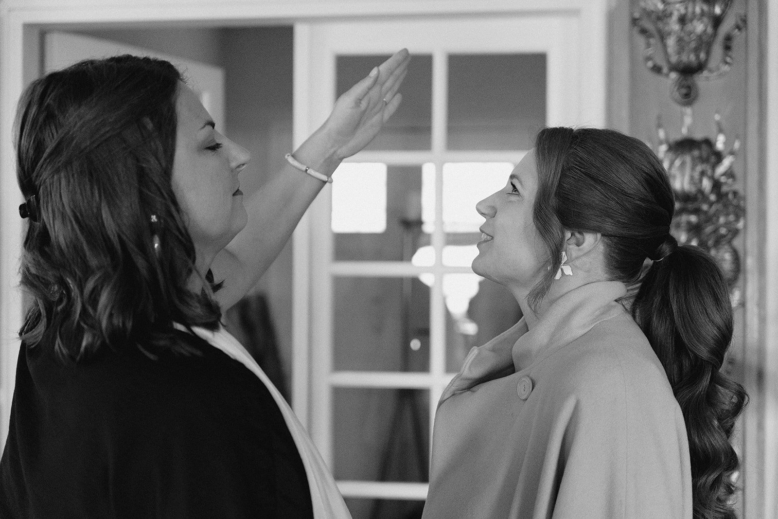 Deux femmes en costume se regardent avec insistance, l'une levant la main vers l'autre.