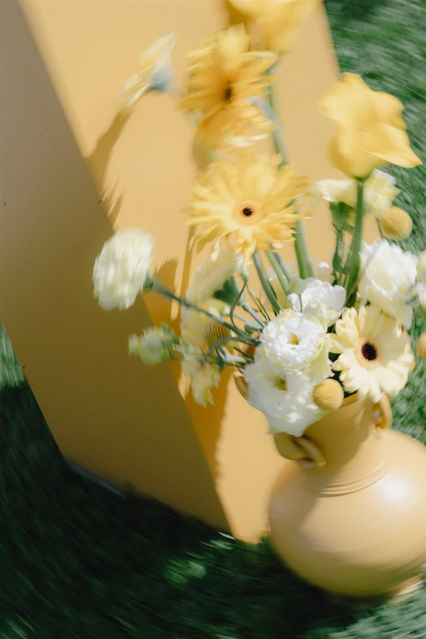 Pupitre jaune décoré avec un bouquet de fleurs jaunes et blanches dans un pot jaune.