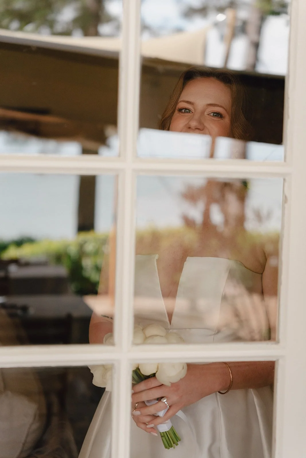 Femme tenant un bouquet de fleurs blanches regardant par une fenêtre