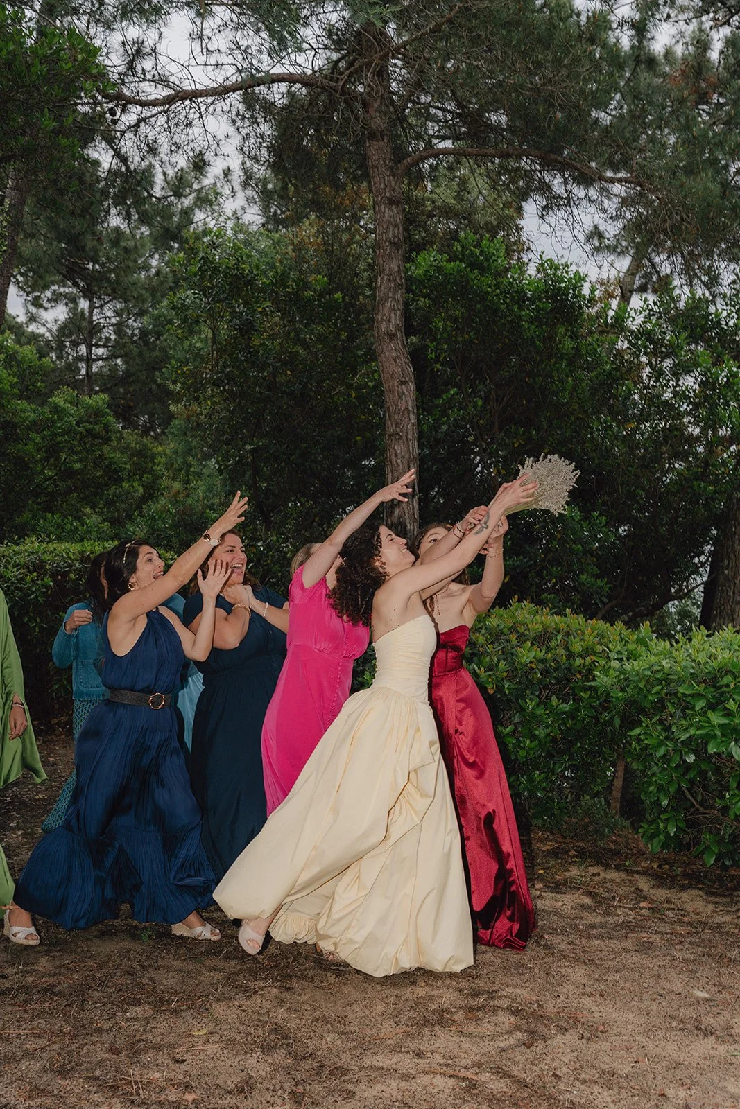 Groupe de femmes à une fête, lançant une cérémonie nuptiale dans un environnement naturel avec des arbres et des buissons.