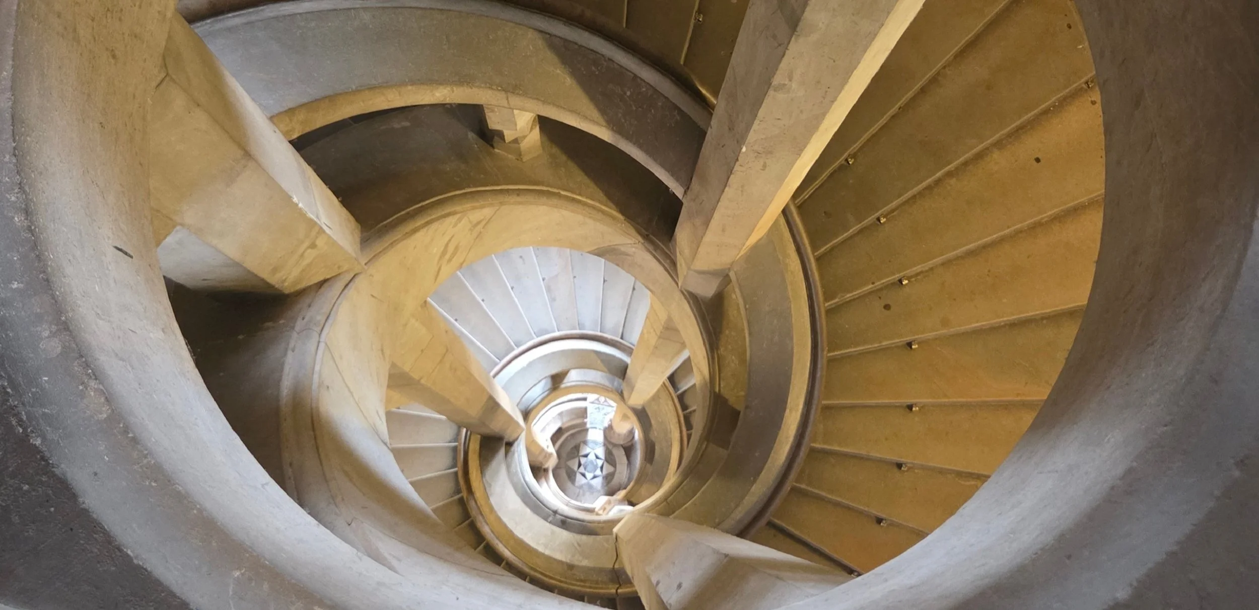 Aufnahme einer Wendeltreppe aus Stein, Blick nach unten zur Basis umgeben von Sandsteinwänden.