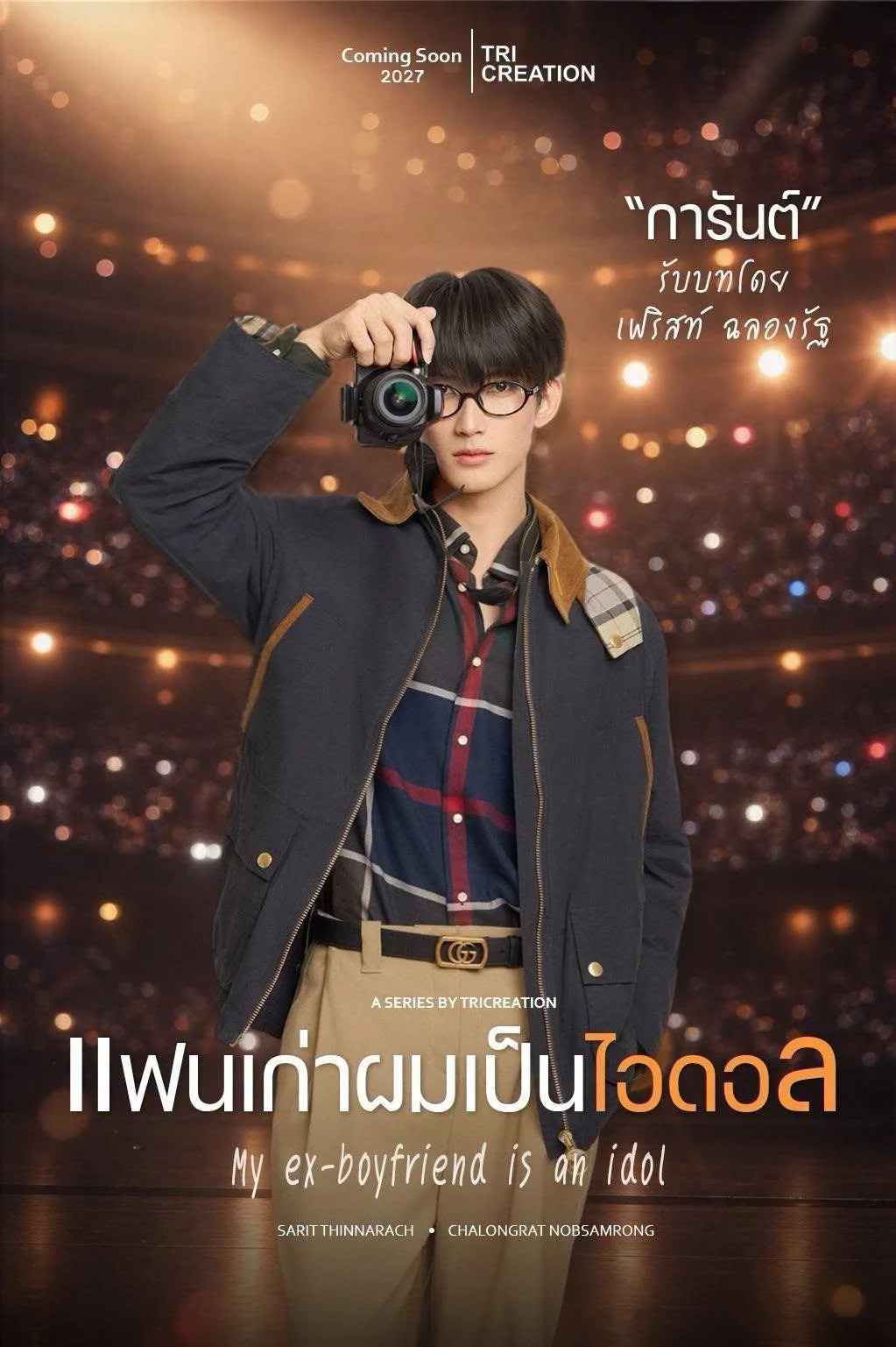 Cover of a series titled 'My ex-boyfriend is an idol' featuring a young man in glasses holding a camera, wearing a plaid shirt and jacket against a blurred cityscape background with bokeh lights, with Thai text and English subtitle.
