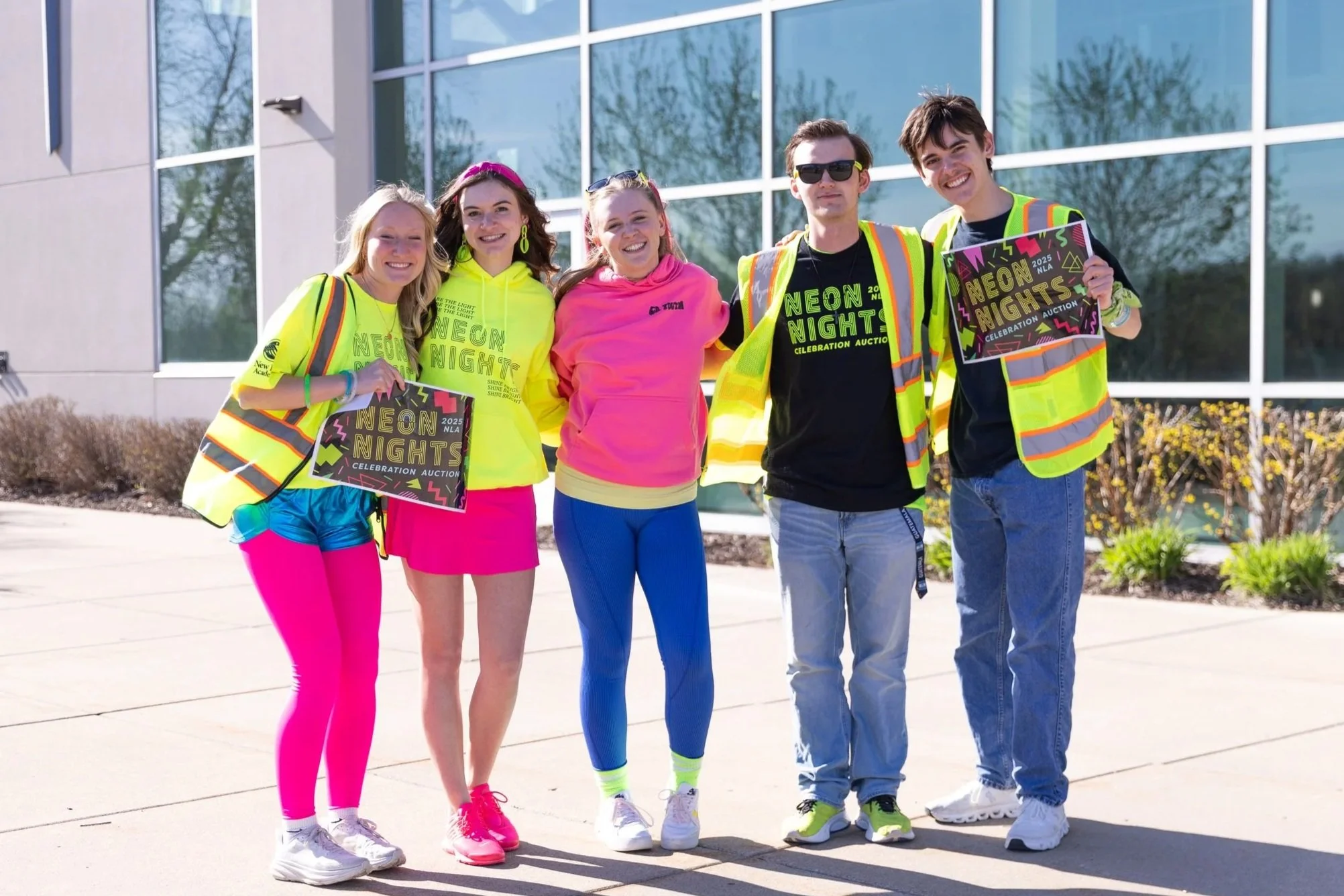 students dressed in neon outfits greeting guests at auction event