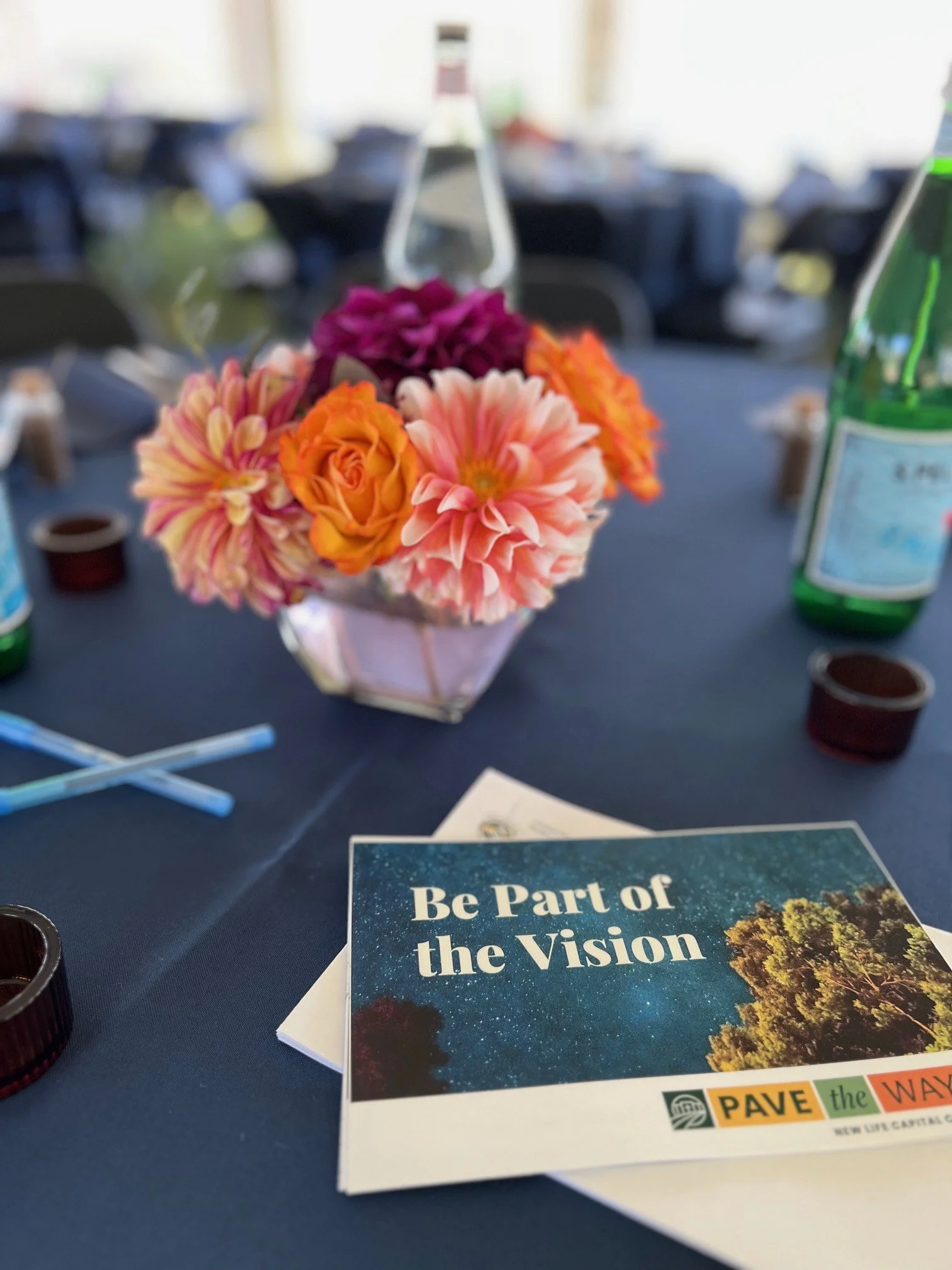 Floral centerpiece with fall colors on a navy tablecloth with a branded response card and envelope.