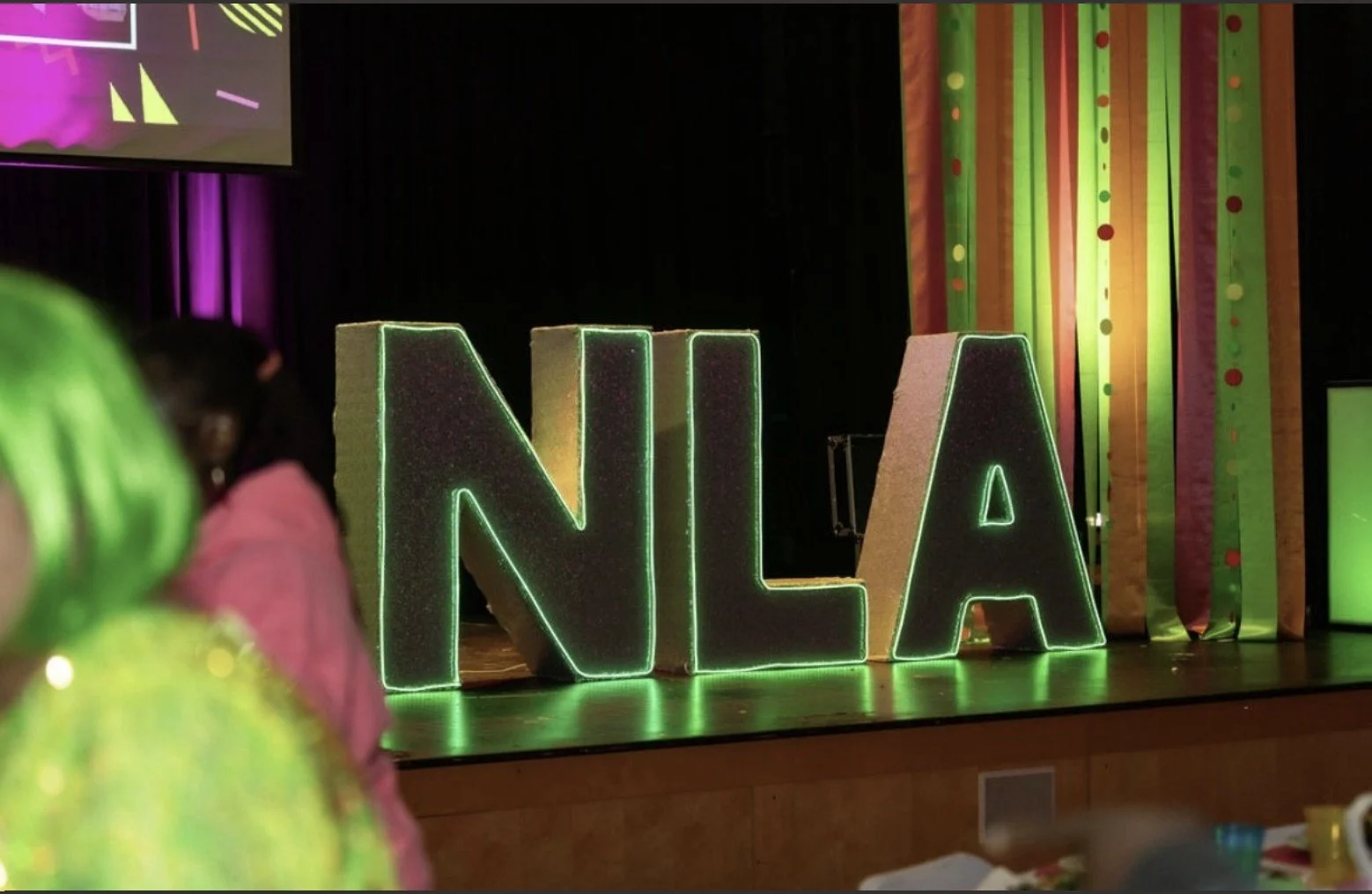 glowing NLA letters on stage for auction event