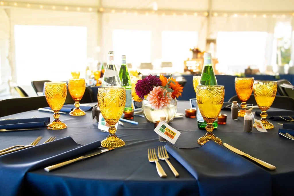 table with navy tablecloth, gold silverware, amber glass cups and fall florals
